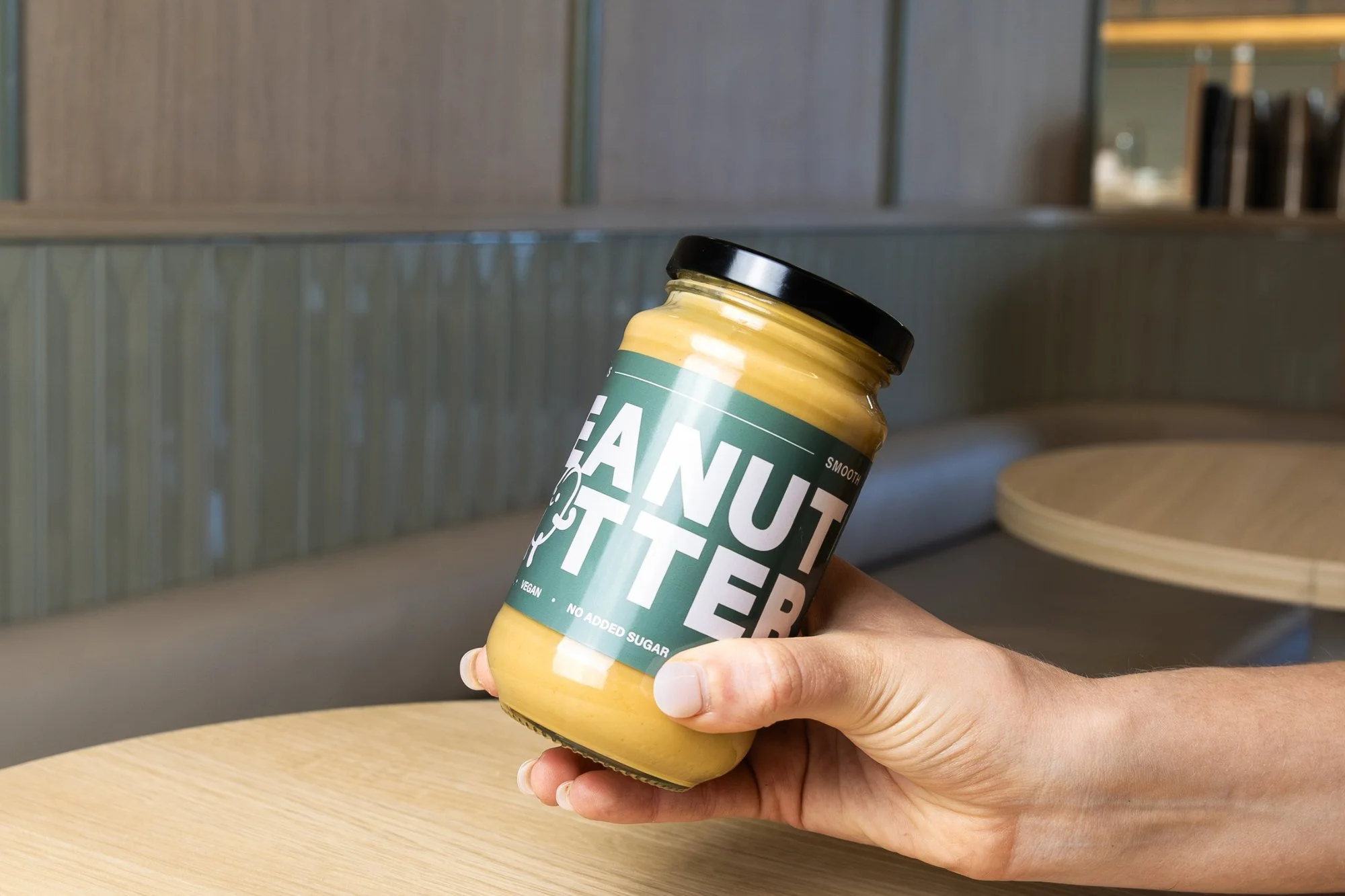 Hand holding a jar of Blitz Bar smooth peanut butter inside a Blitz Bar store in Melbourne