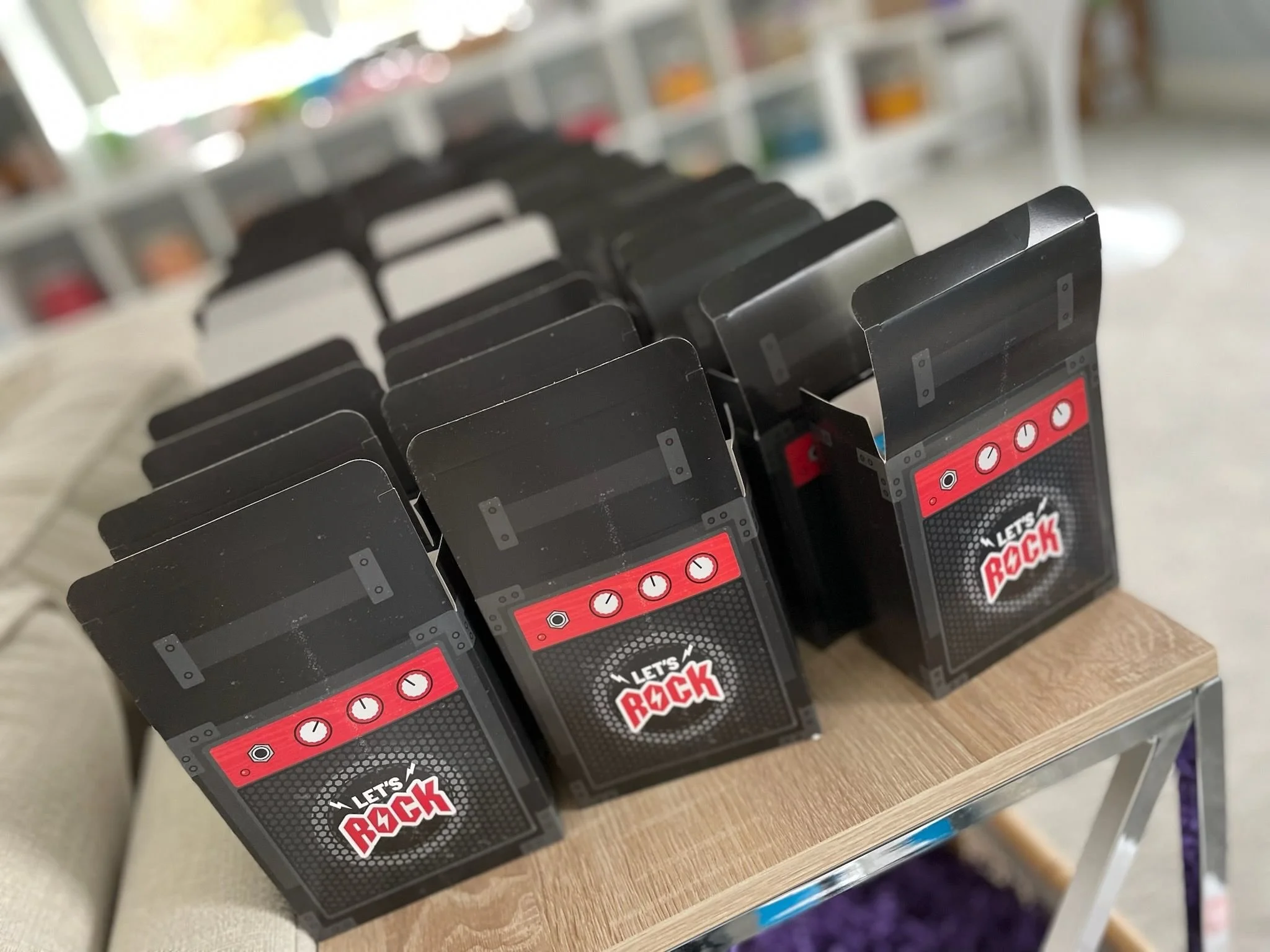 Multiple black guitar-shaped boxes with a 'Let's Rock' logo and clock icons stacked on a wooden table.