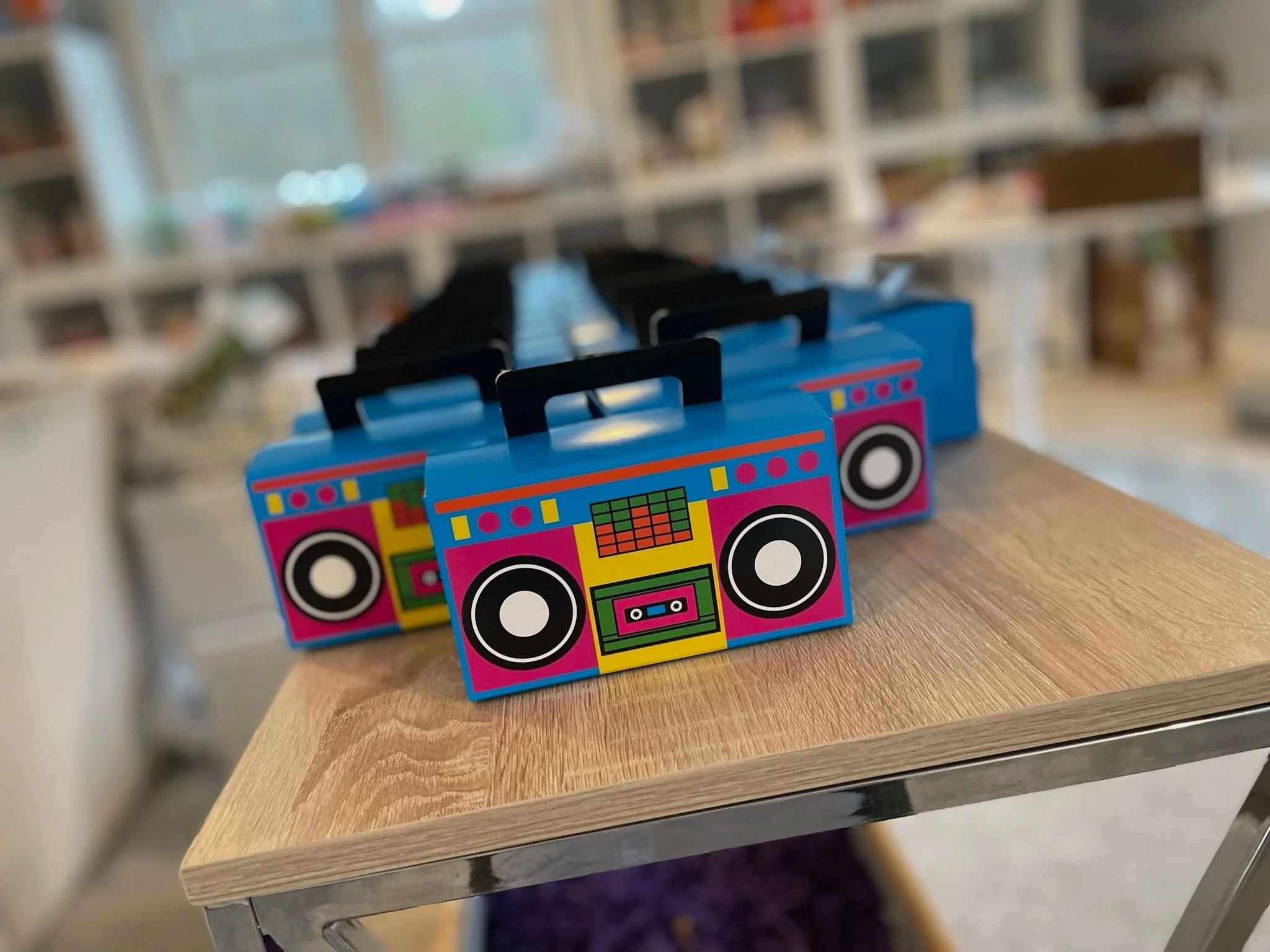 Custom birthday party favors featuring a colorful toy radio with a boombox design on a wooden table.