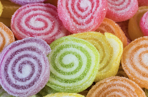 Colorful spiral-shaped gummy candies in pink, purple, green, yellow, and orange with sugar coating.