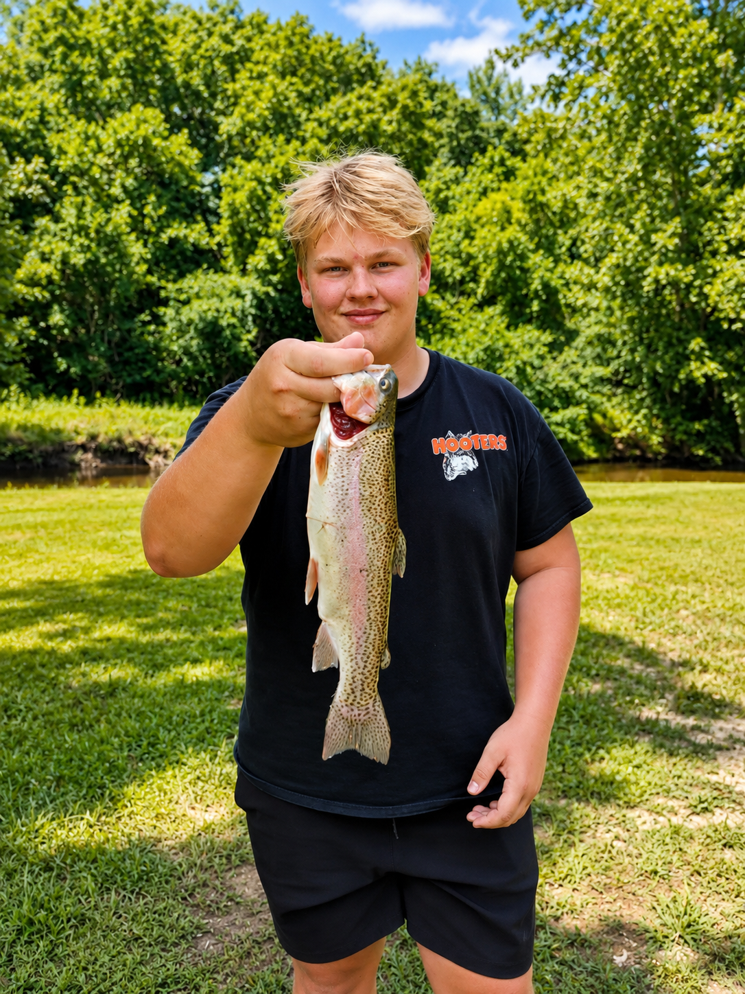 Camper holding a freshly caught fish beside the creek at Camp Creekside.
