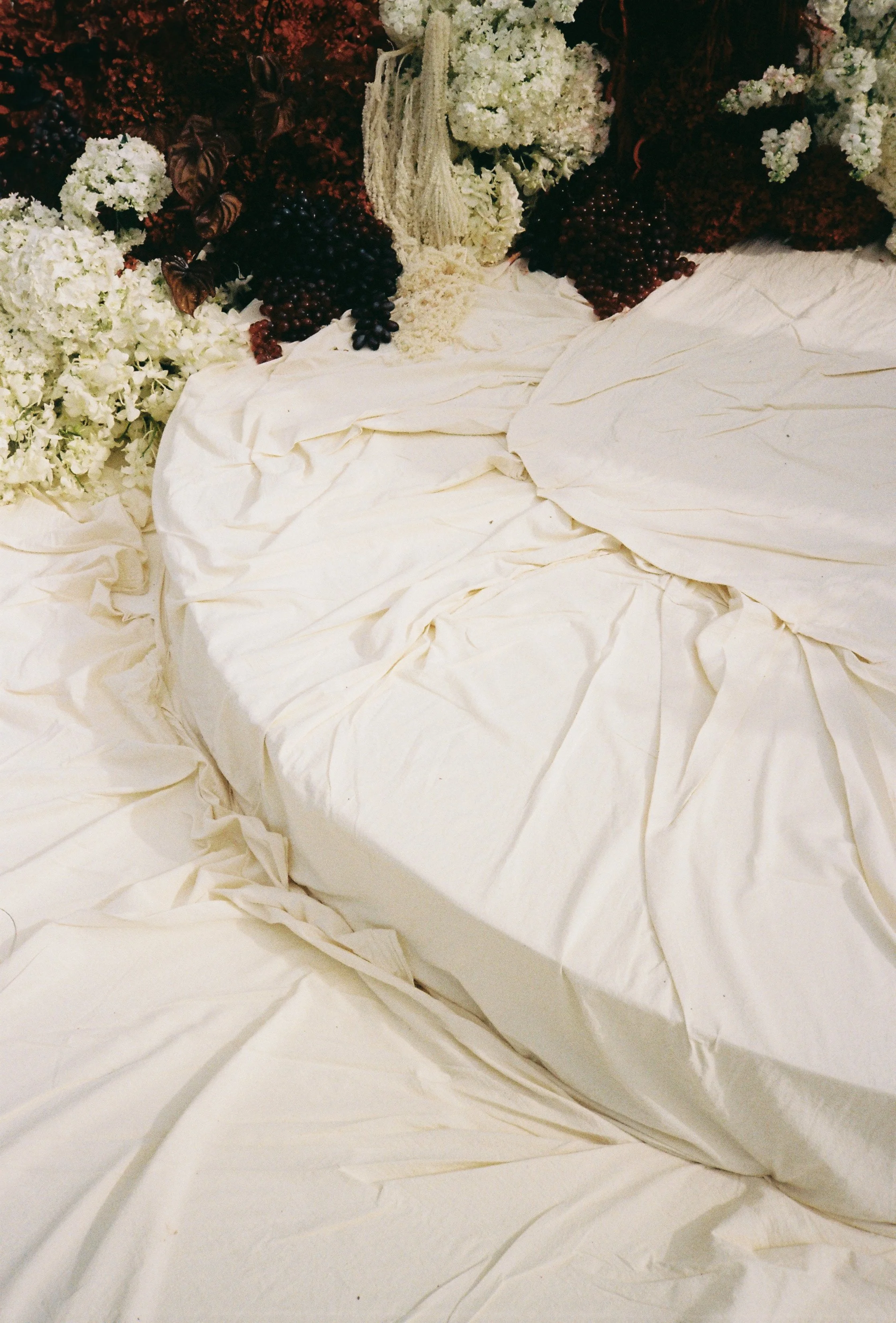 Layered ivory draping on sri panwa ceremony stage with textured floral arrangements and deep red accents