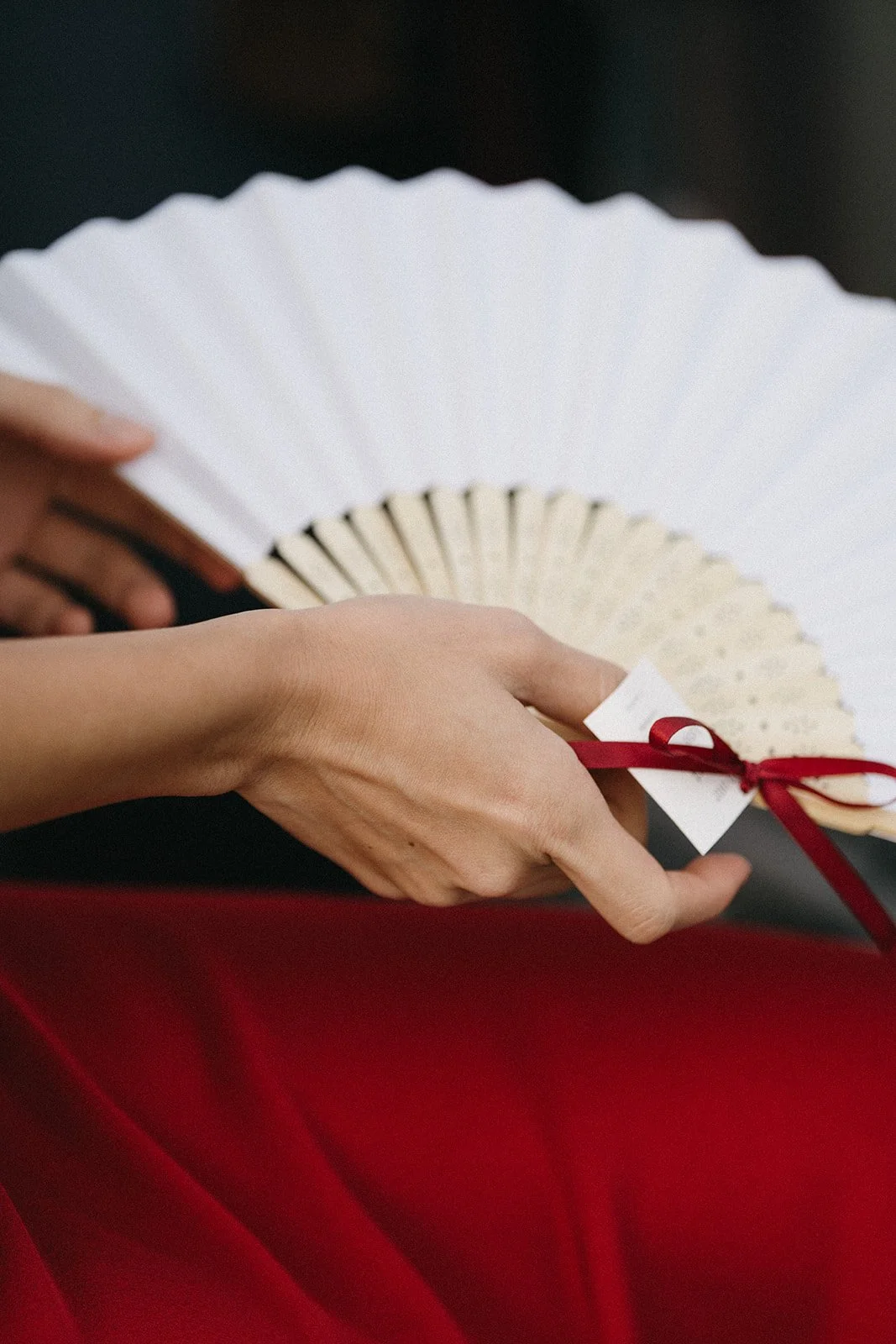 a white folding fan with a red ribbon