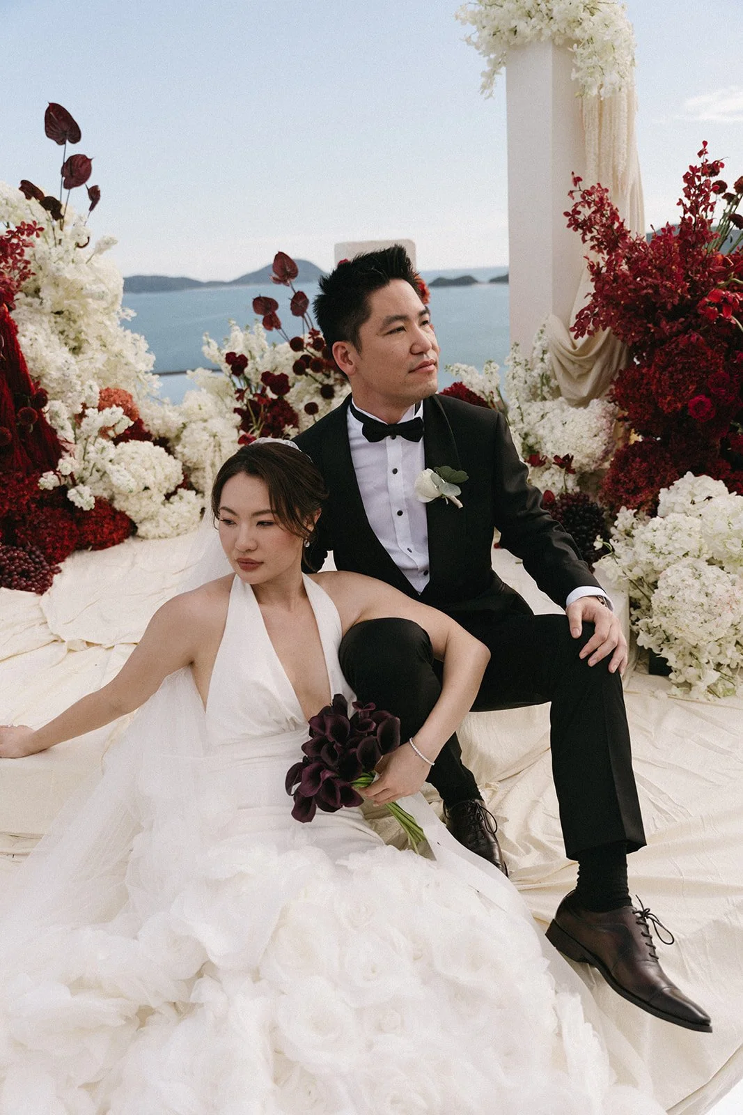 couple posing in front of red and white ceremony backdrop at Phuket wedding