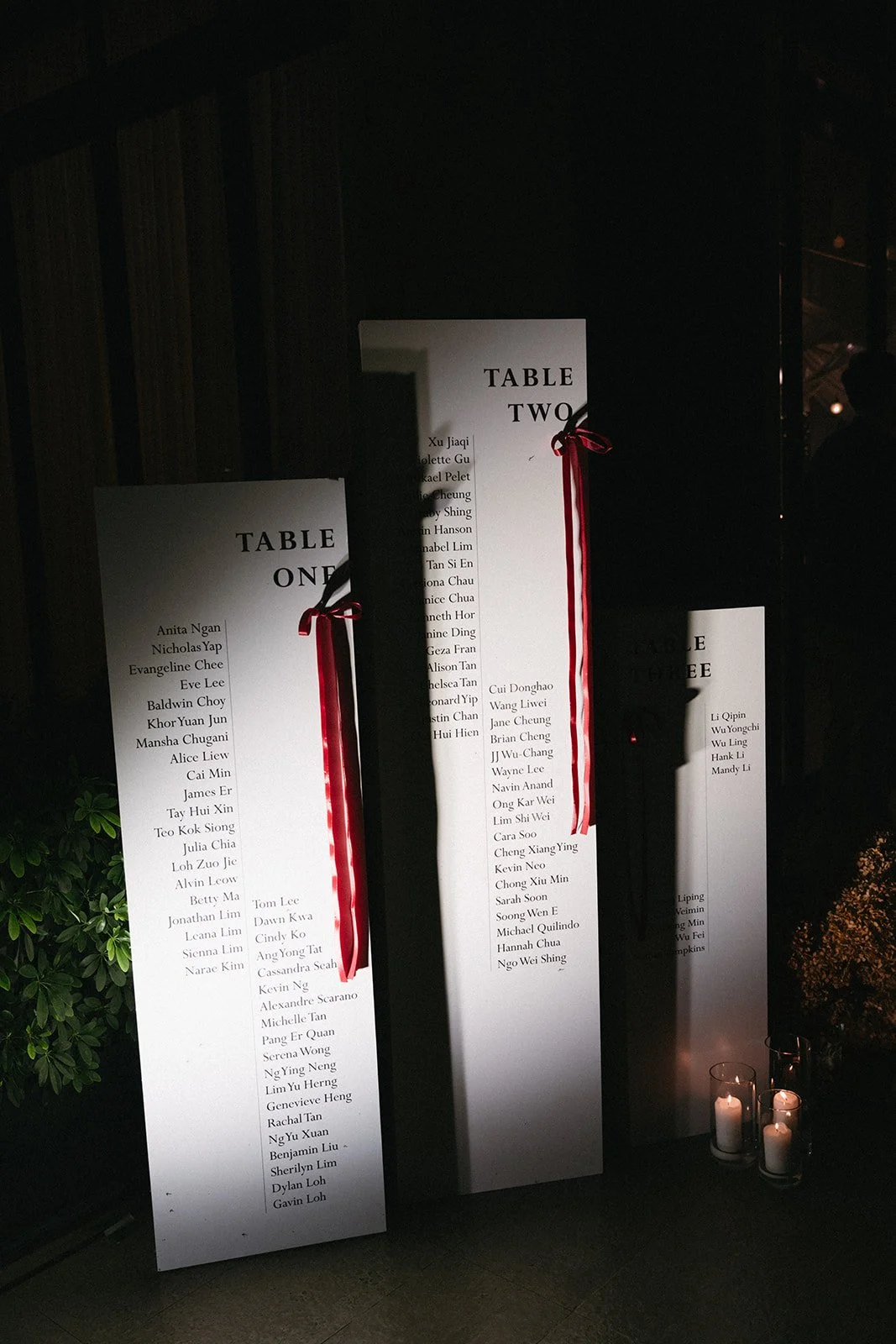 Tall modern white table seating chart with red ribbon accents for luxury Phuket wedding reception