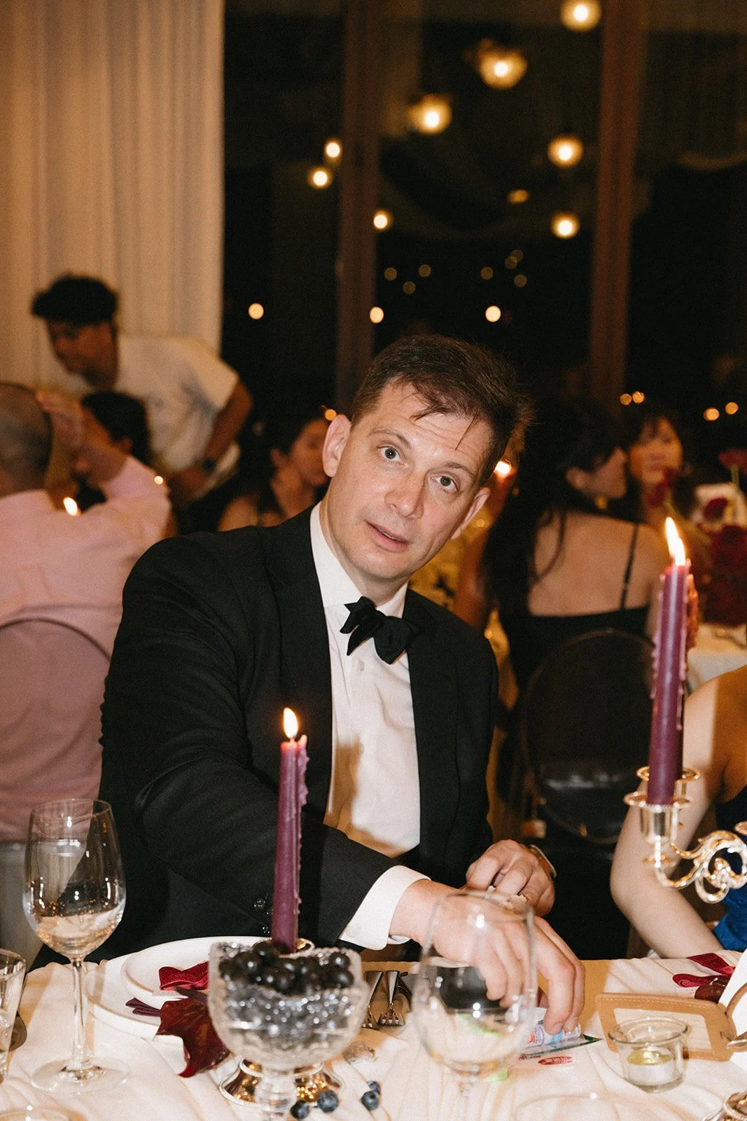 guest at candlelit wedding dinner surrounded by elegant wine and berry-toned decor in Phuket