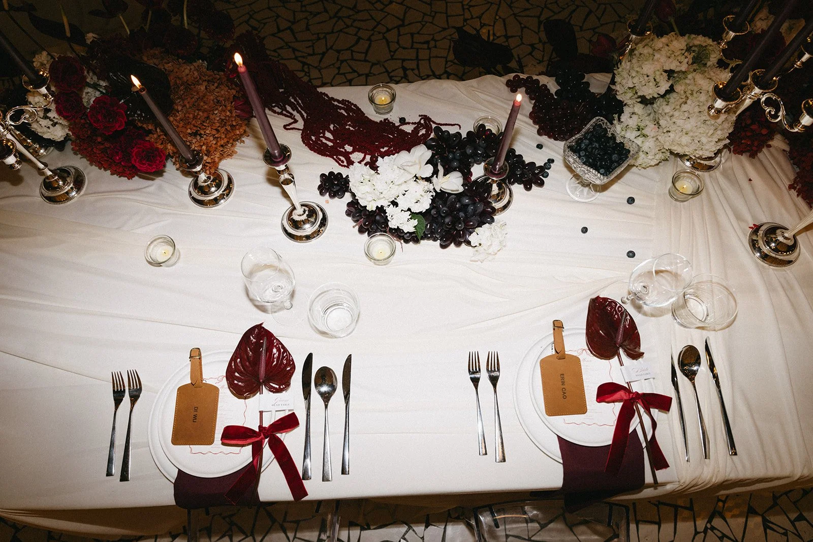 Flat lay of wedding tablescape with sculptural florals, folded napkins, gift tags and black cutlery at Phuket wedding reception