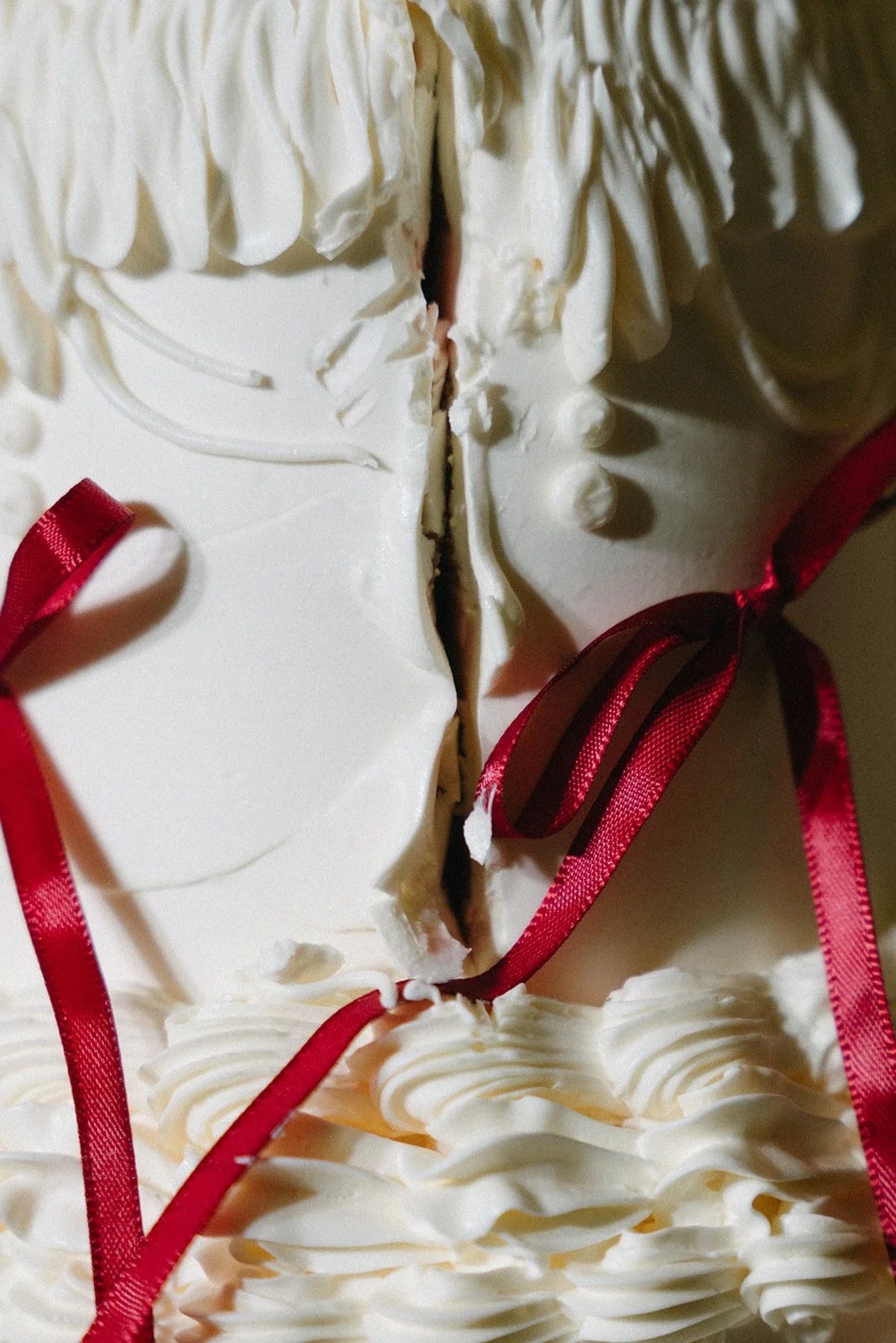 close up of wedding cake with red ribbon and icing detailing