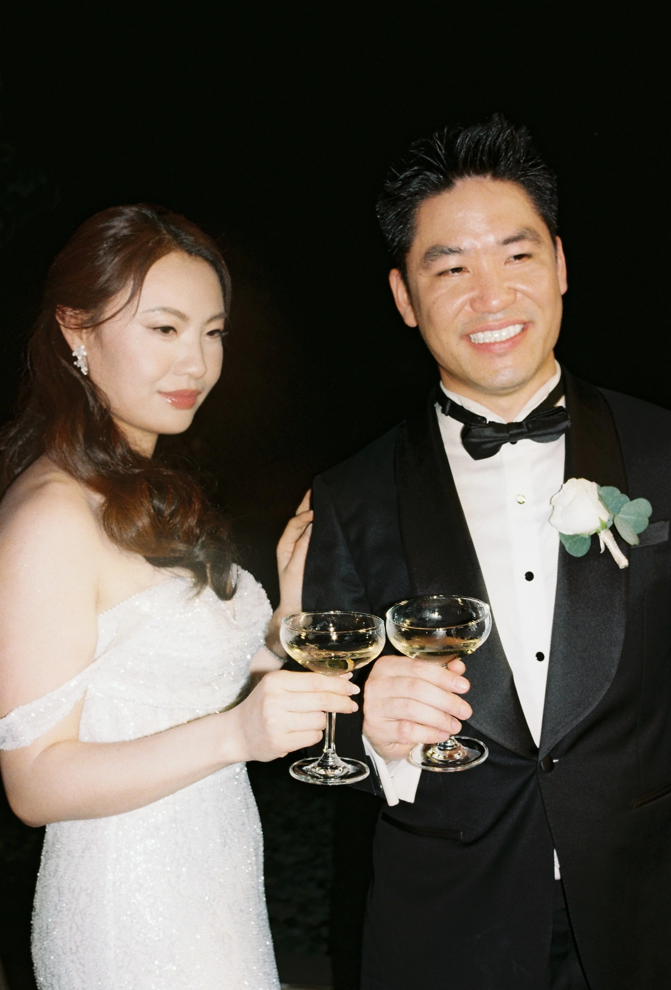 candid film portrait of bride and groom holding cocktails at sri panwa wedding reception