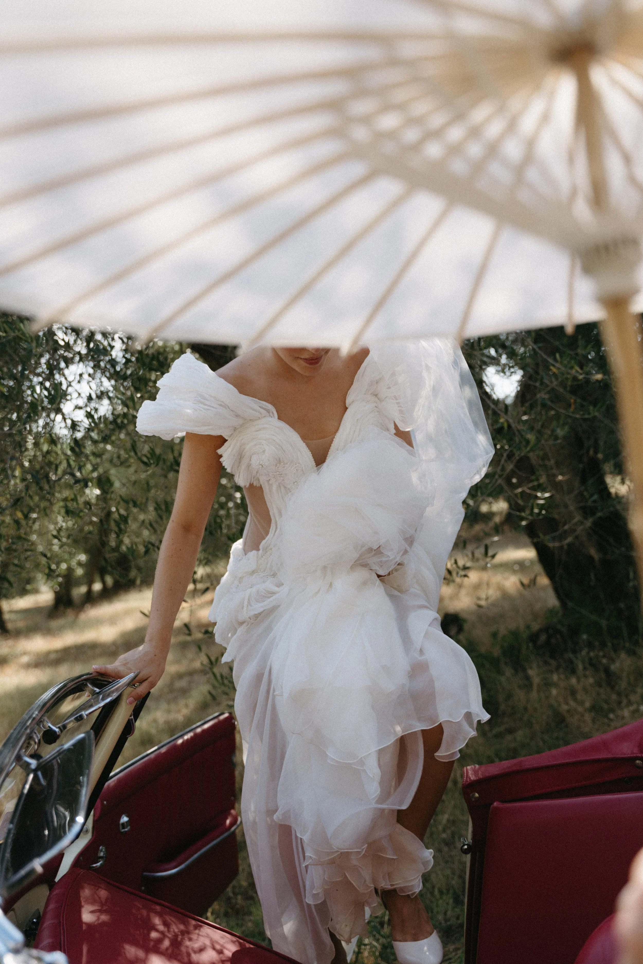 Bride wearing Rara Avis Gabriella gown with detachable sheer skirt beside vintage Mercedes