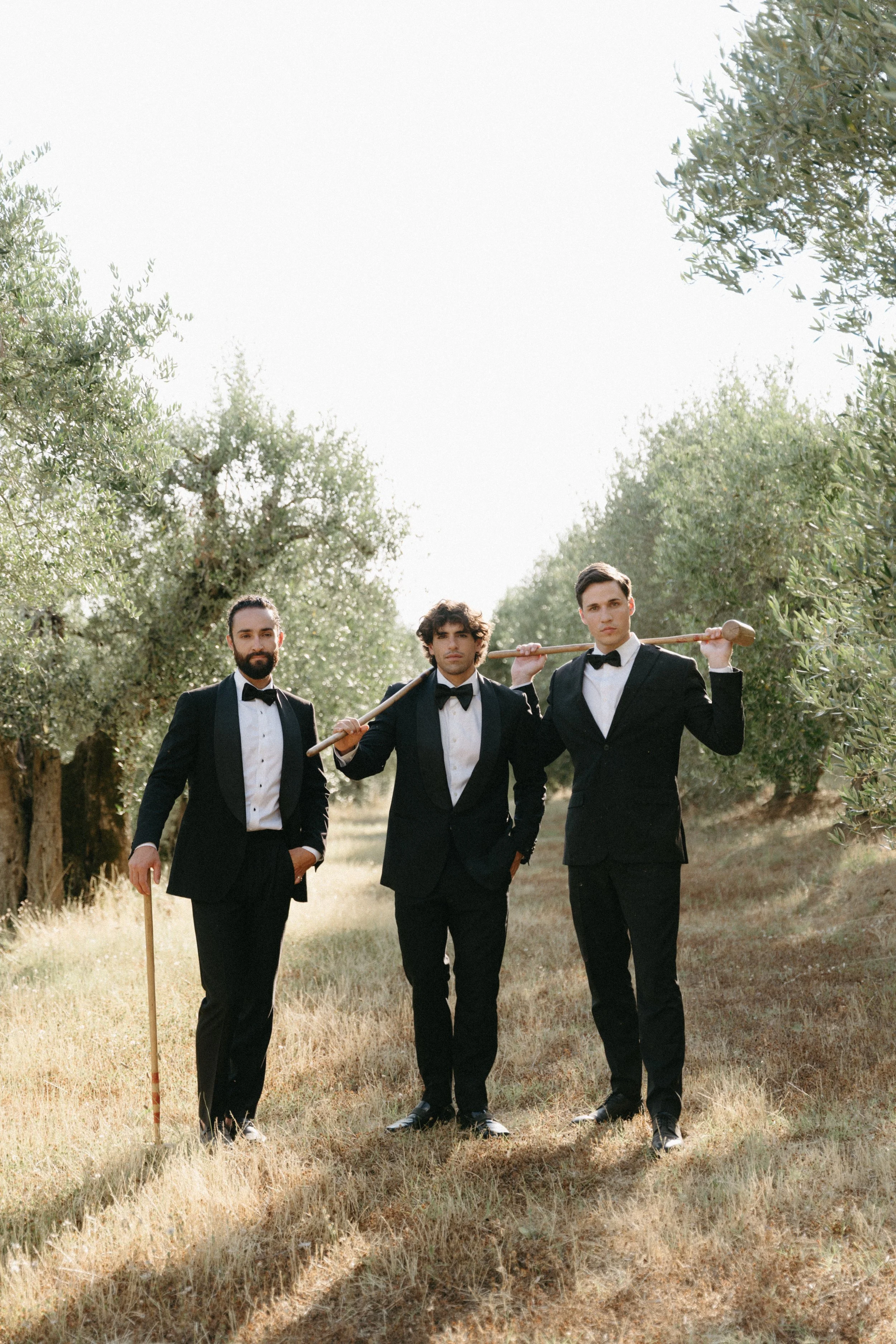 groom posing with groomsmen amongst the olive trees at tuscany wedding venue