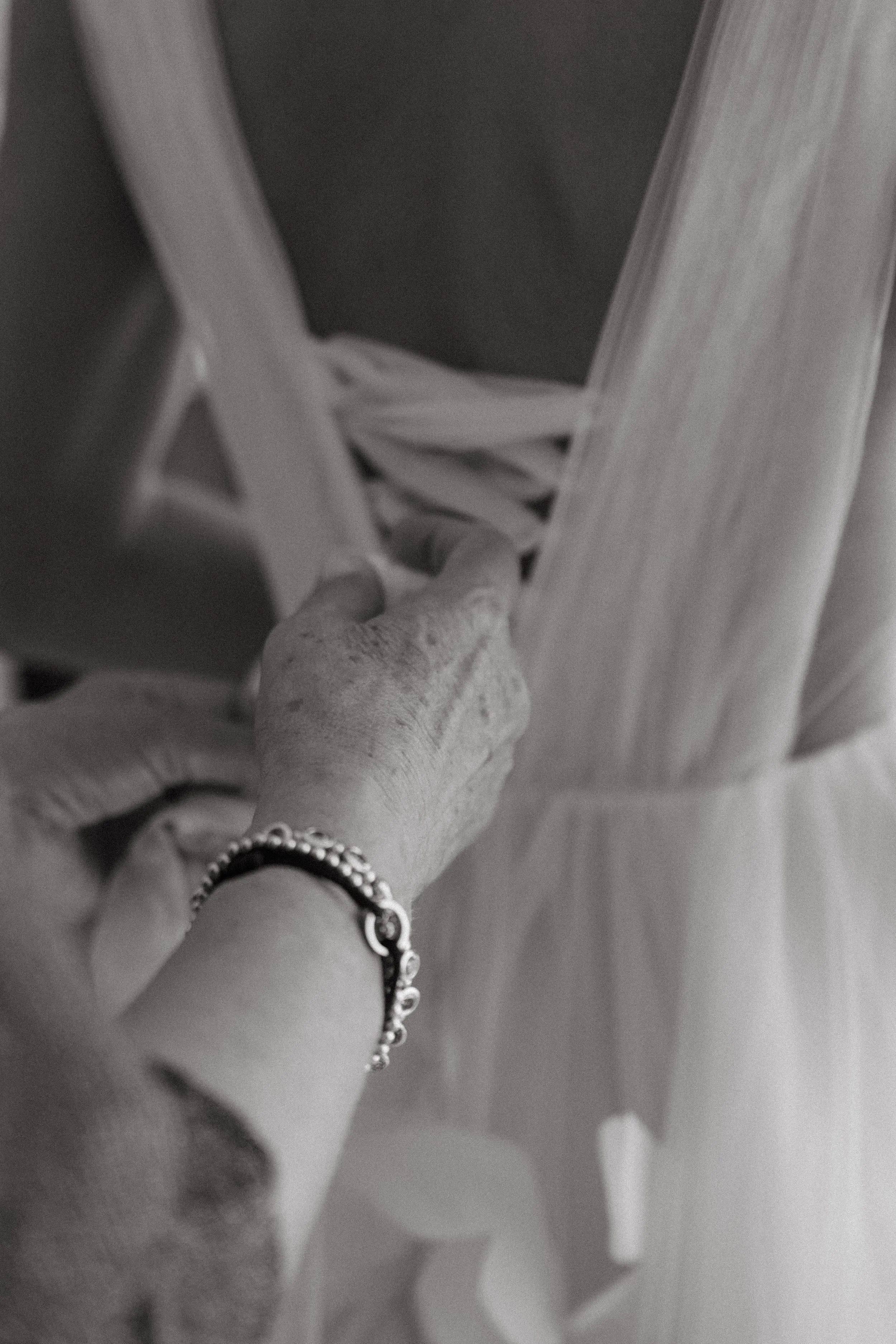 detail shot of bride's mum tying the ribbons on the back of the dress