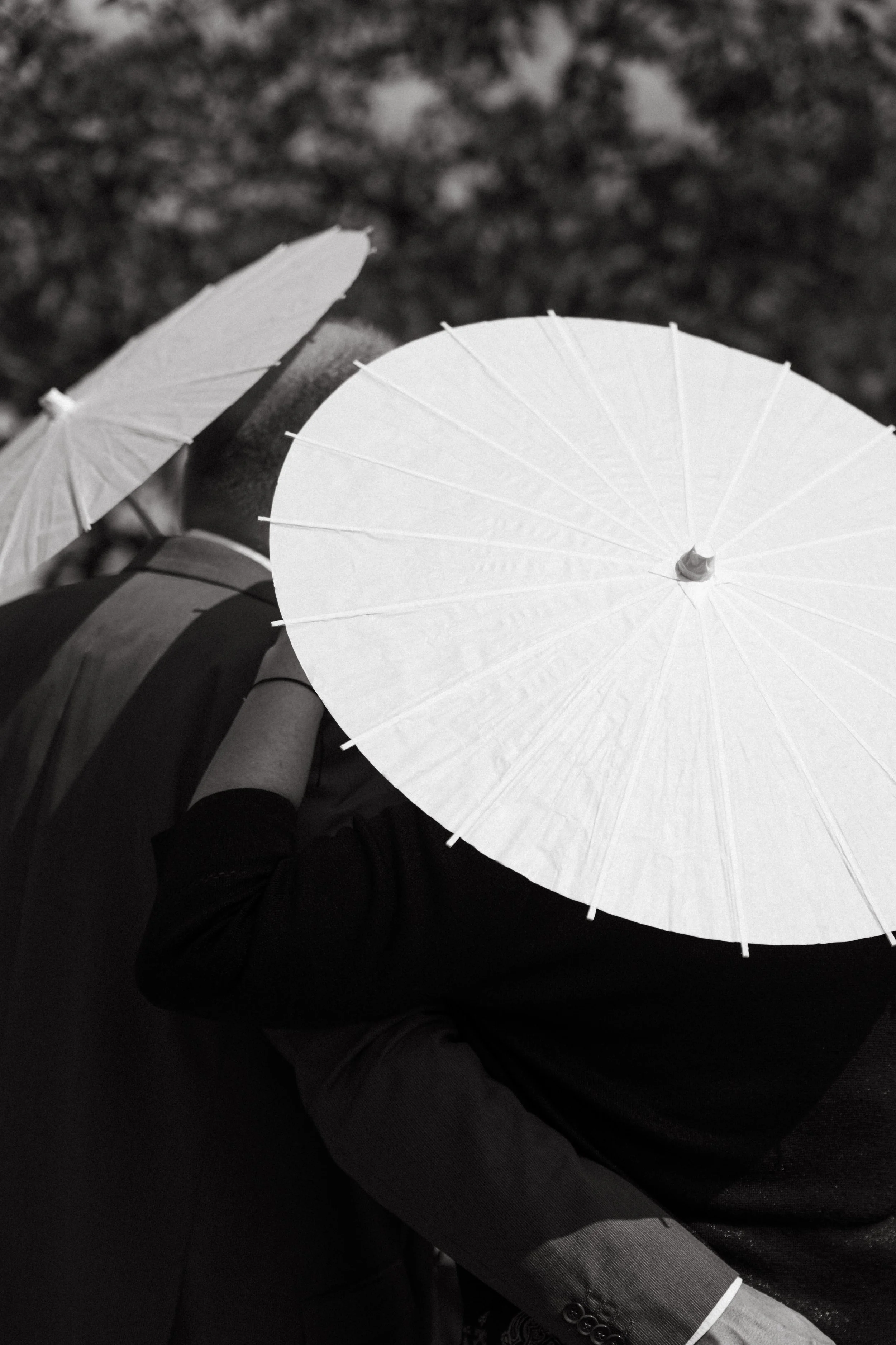 white parasols prepared for guests at the outdoor wedding ceremony