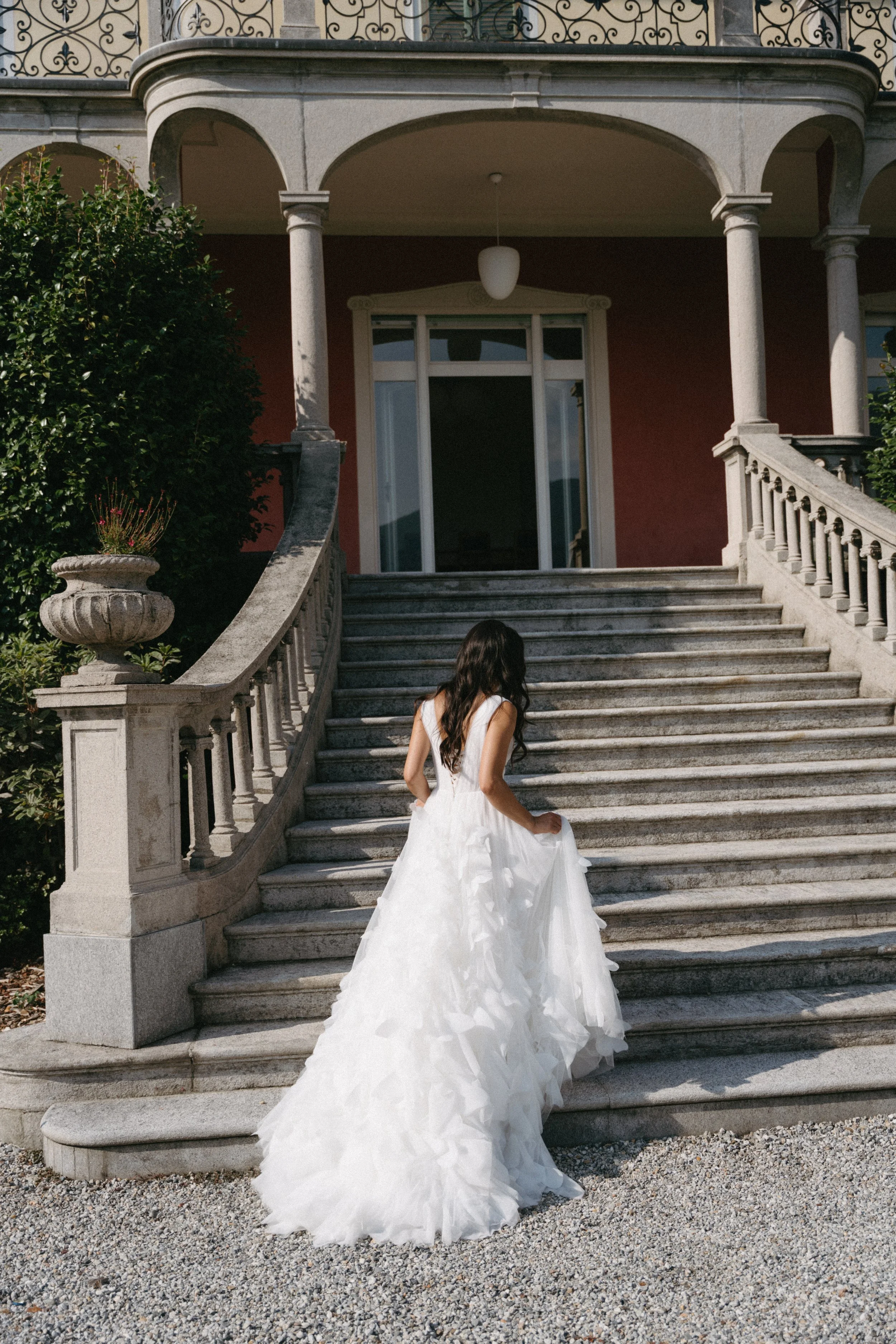 bride holding dress as she climbs the stairs at Villa San Quirico