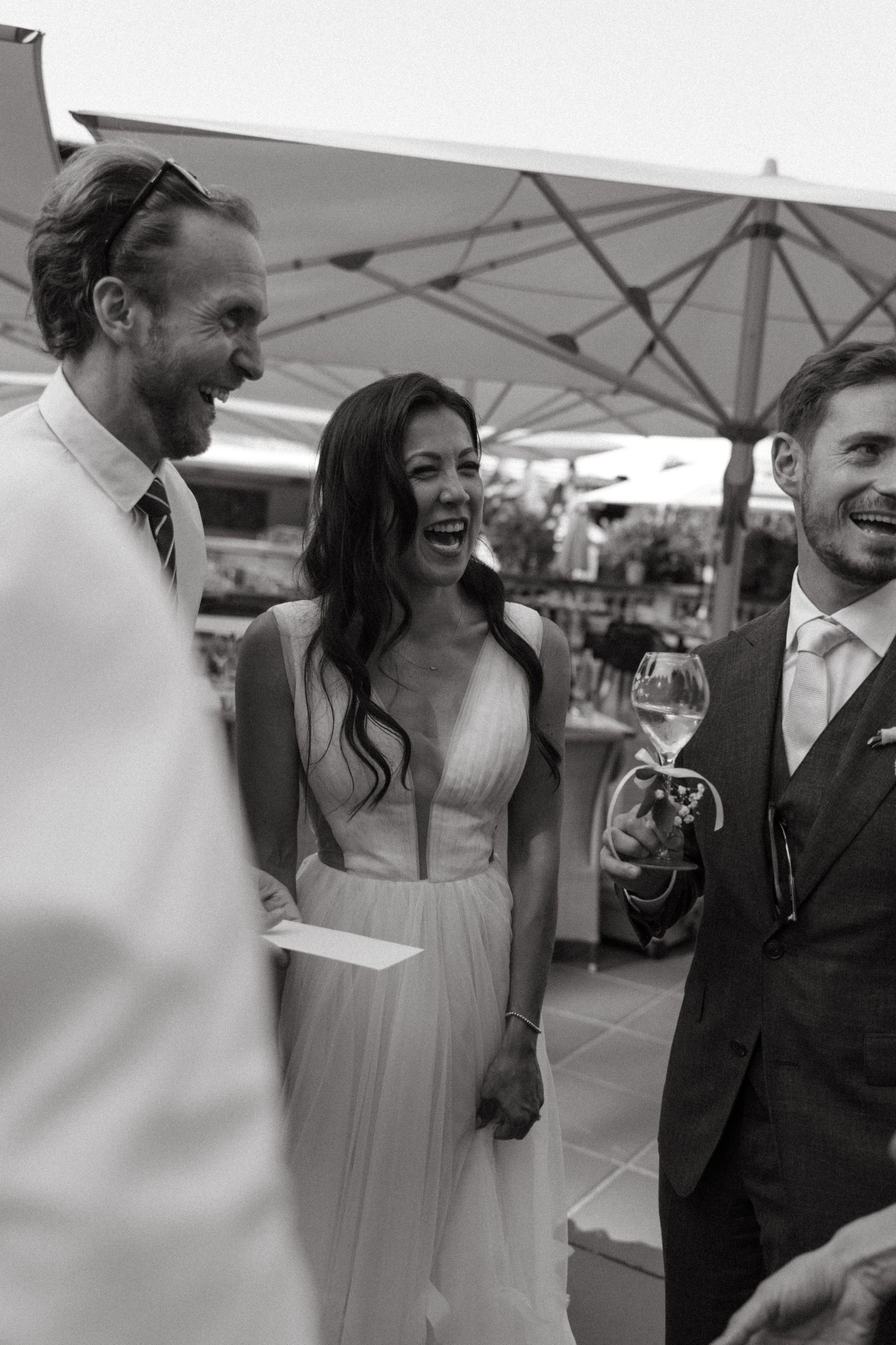 Bride and groom sharing a toast surrounded by friends and family