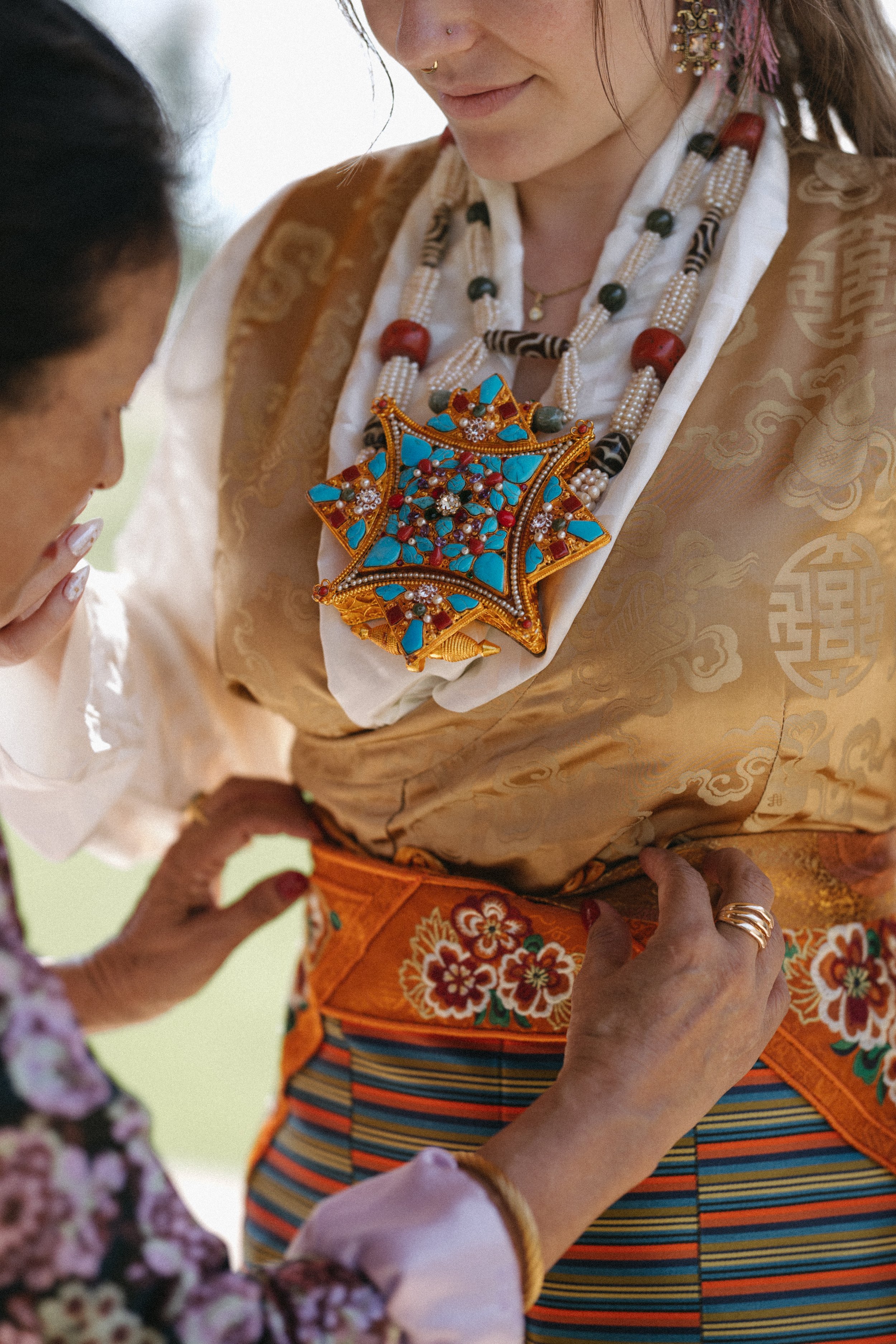 close up shot of groom's mum helping bride with traditional wedding attire
