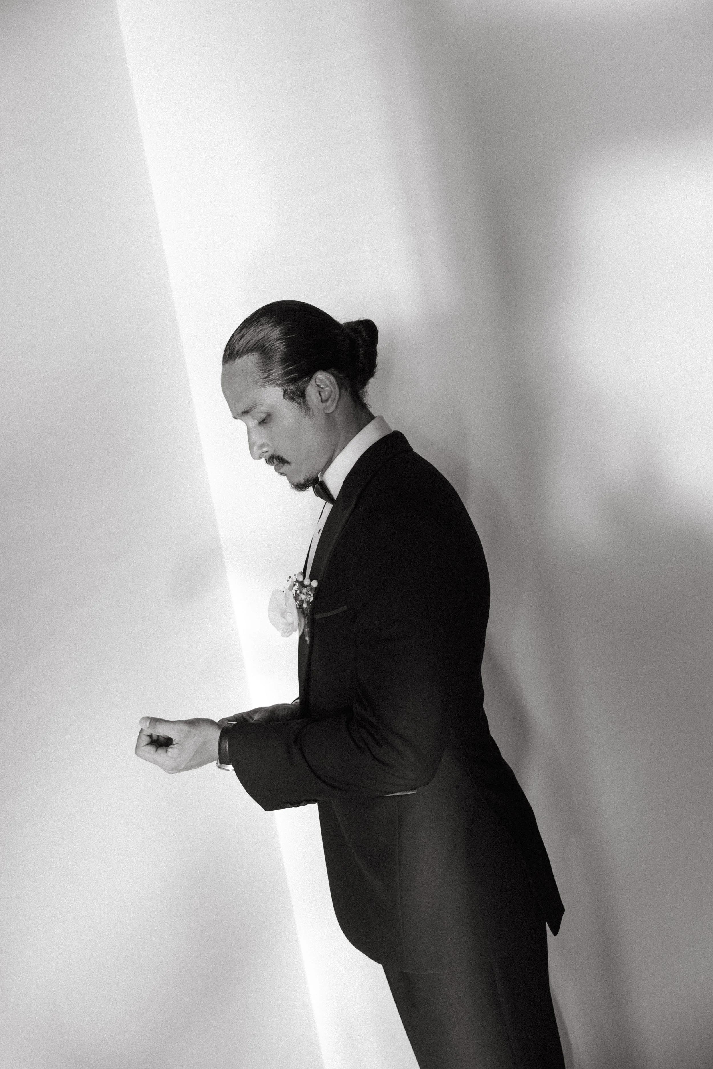 editorial shot of groom wearing black tux and adjusting wrist watch