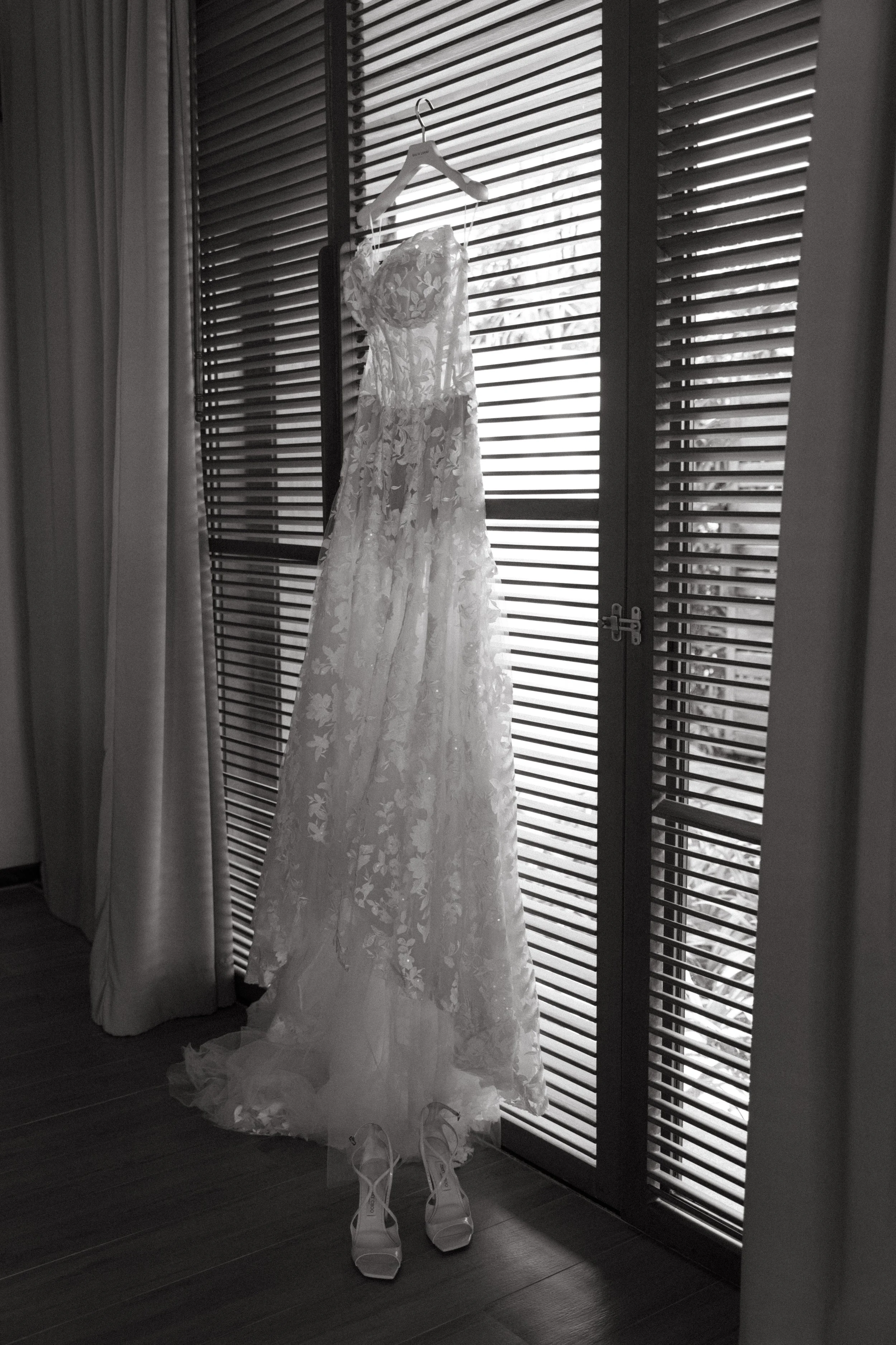 shot of galia lahav wedding gown hanging by the window inside the villa