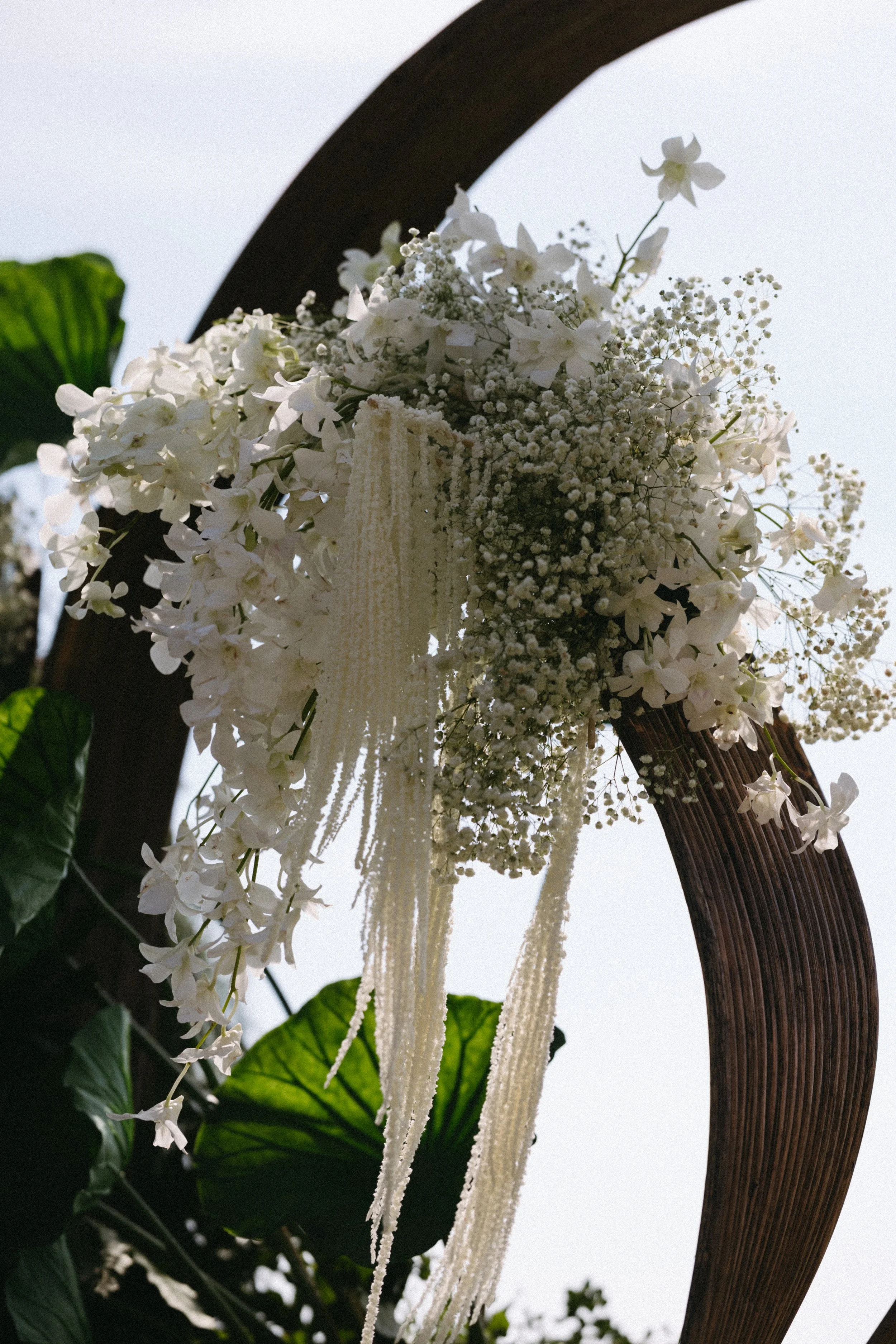 close up shot of an assortment of white and green florals used for the wedding arch