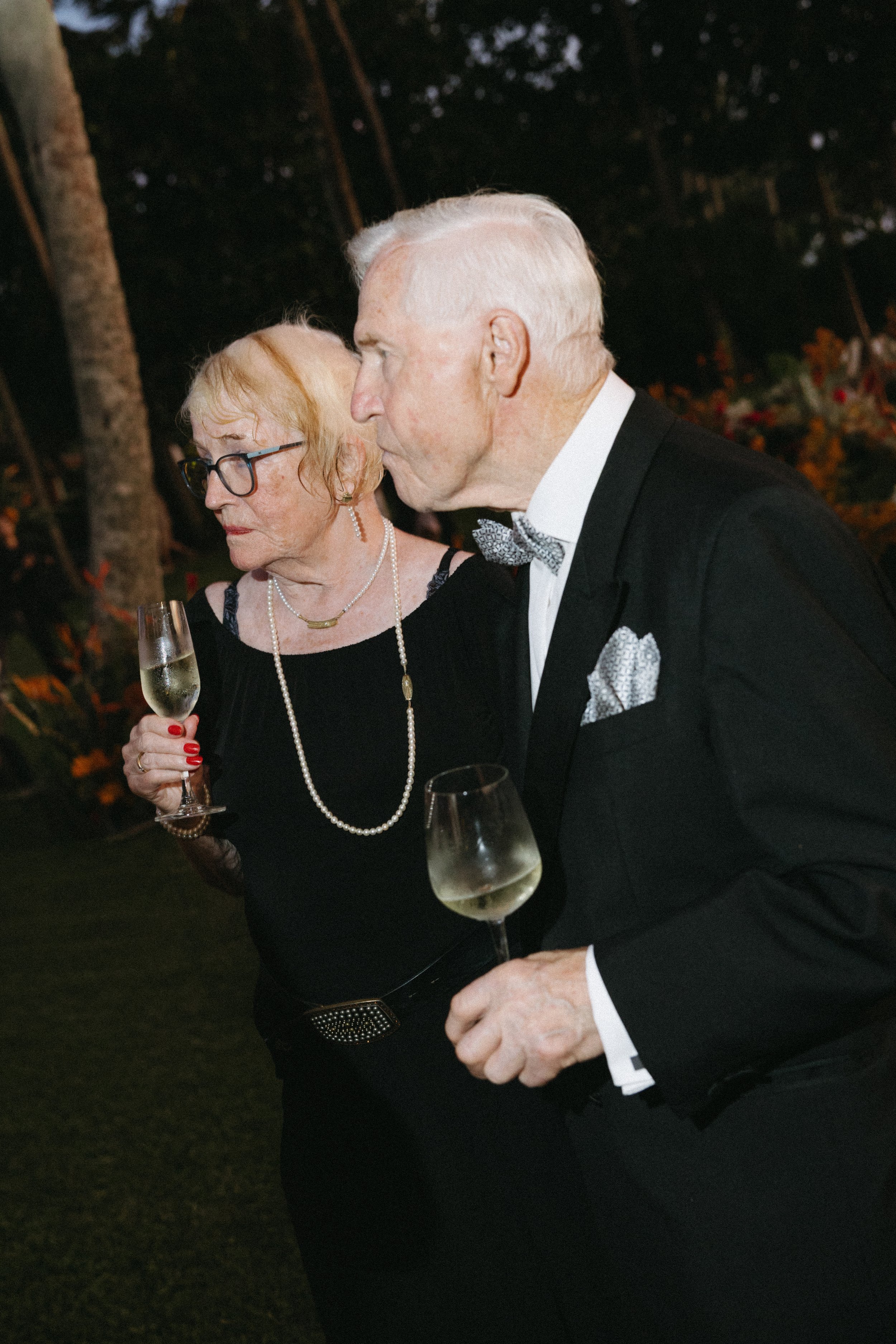 bride's parents holding drinks and listening to speeches during wedding reception 