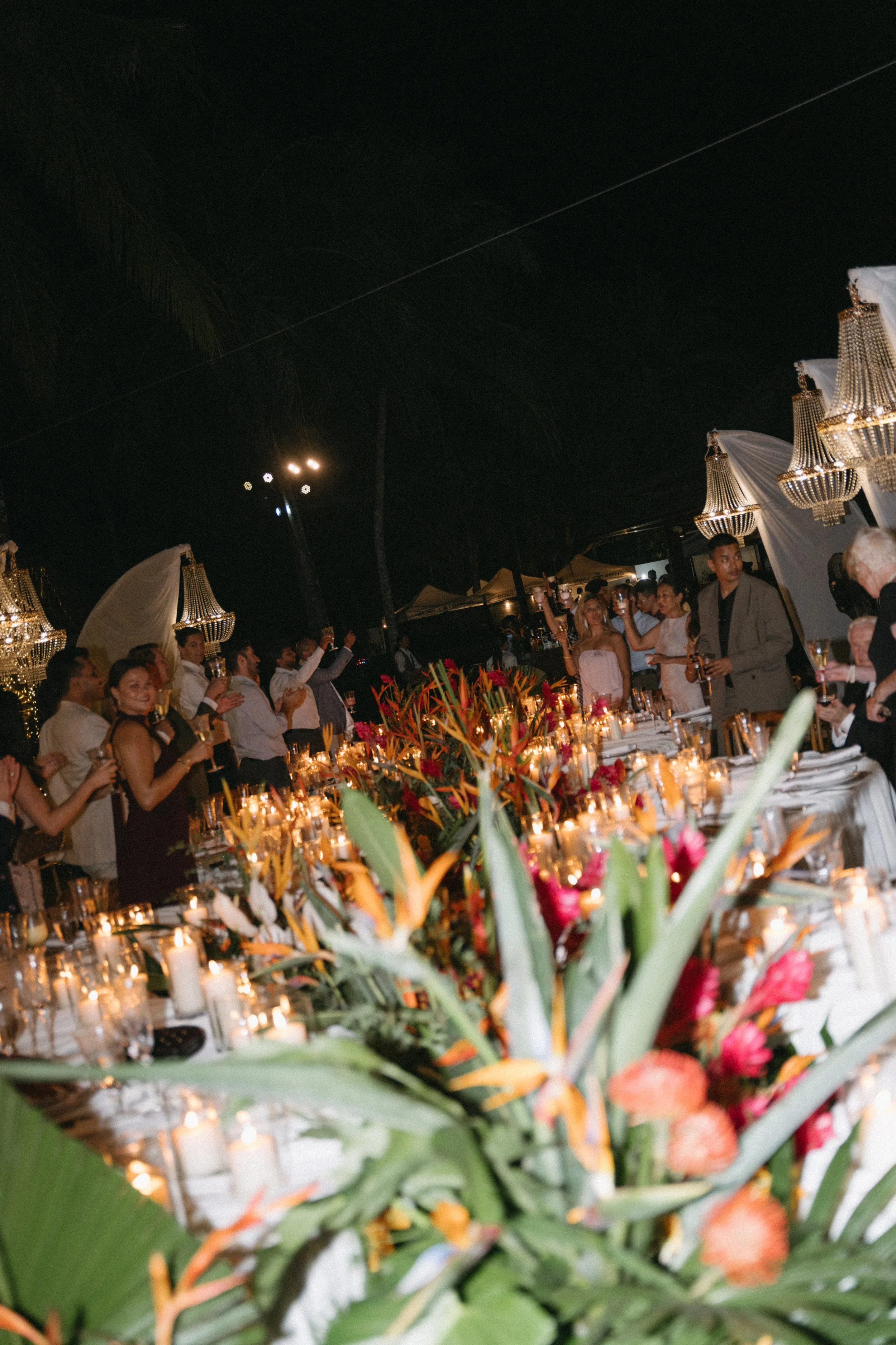 candid shot of guests clapping and toasting during intimate outdoor wedding reception in phang nga