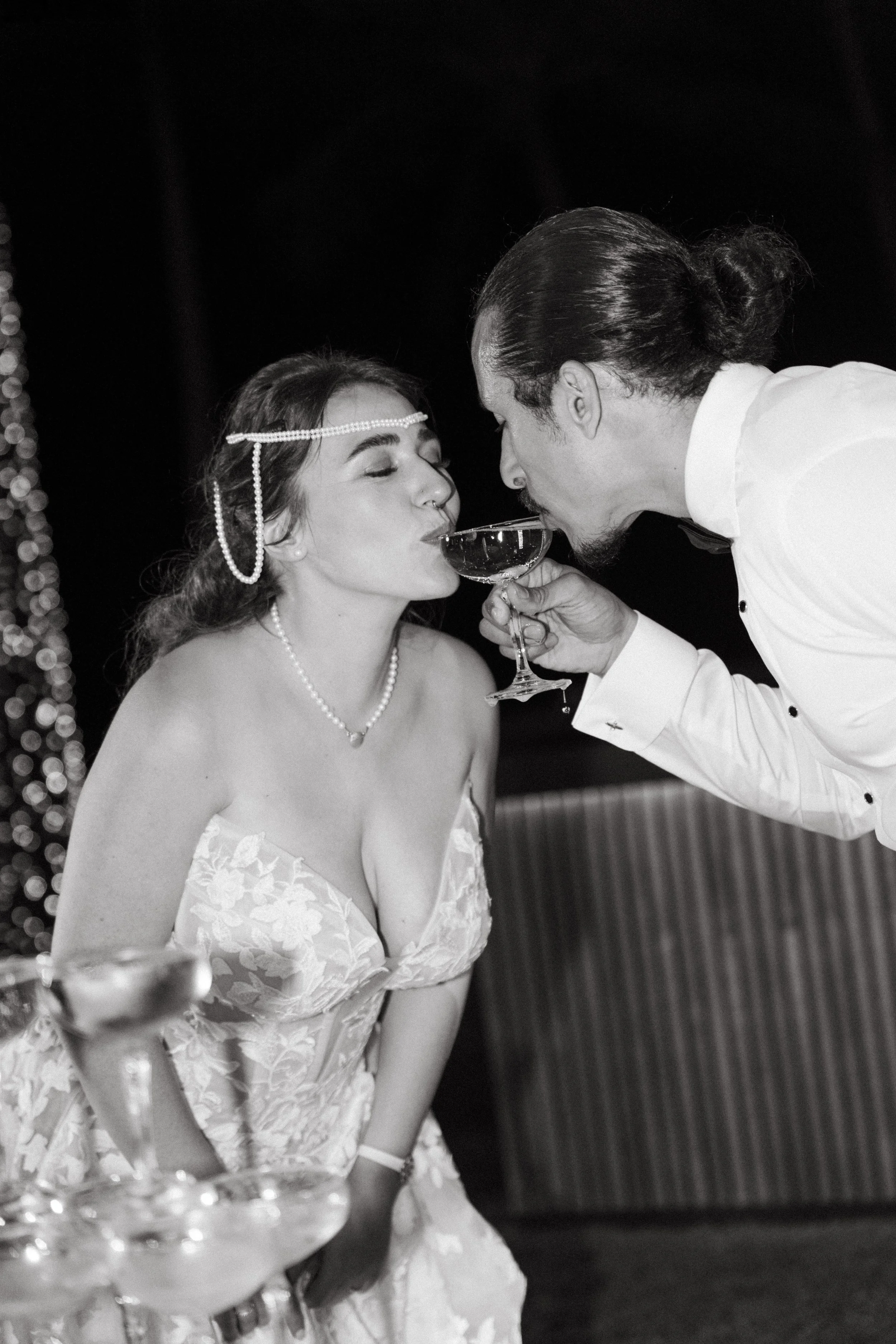 couple sharing a sip from champagne tower glass