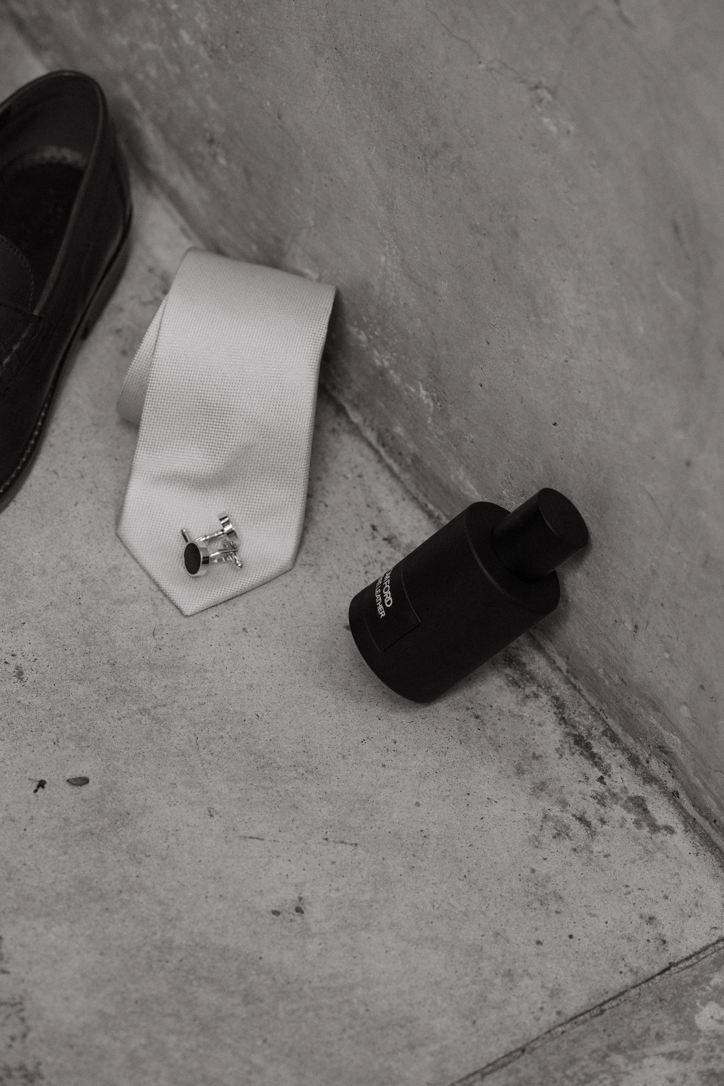 detail shot of groom's accessories  against concrete surface