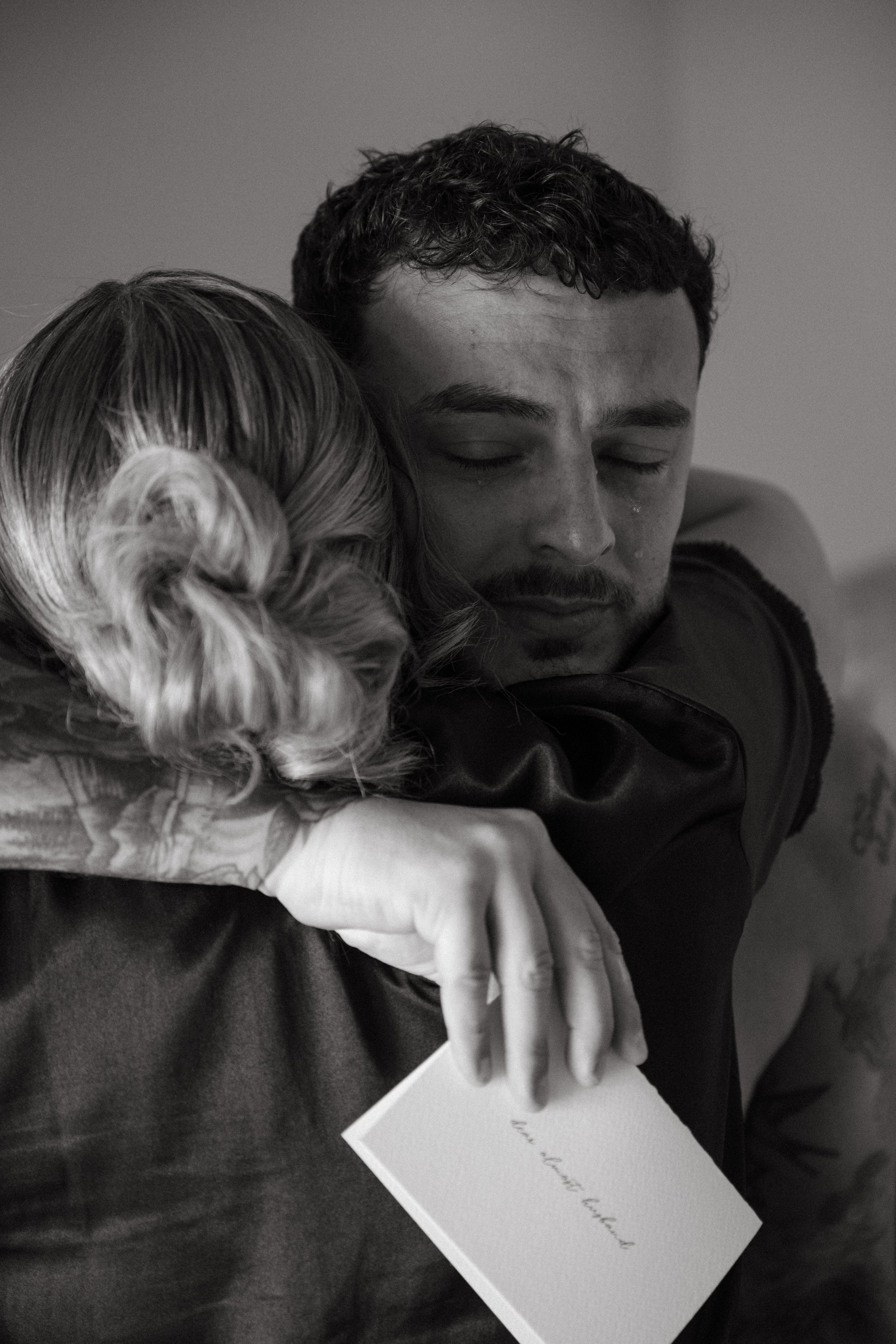 close up of groom hugging his friend while holding the card