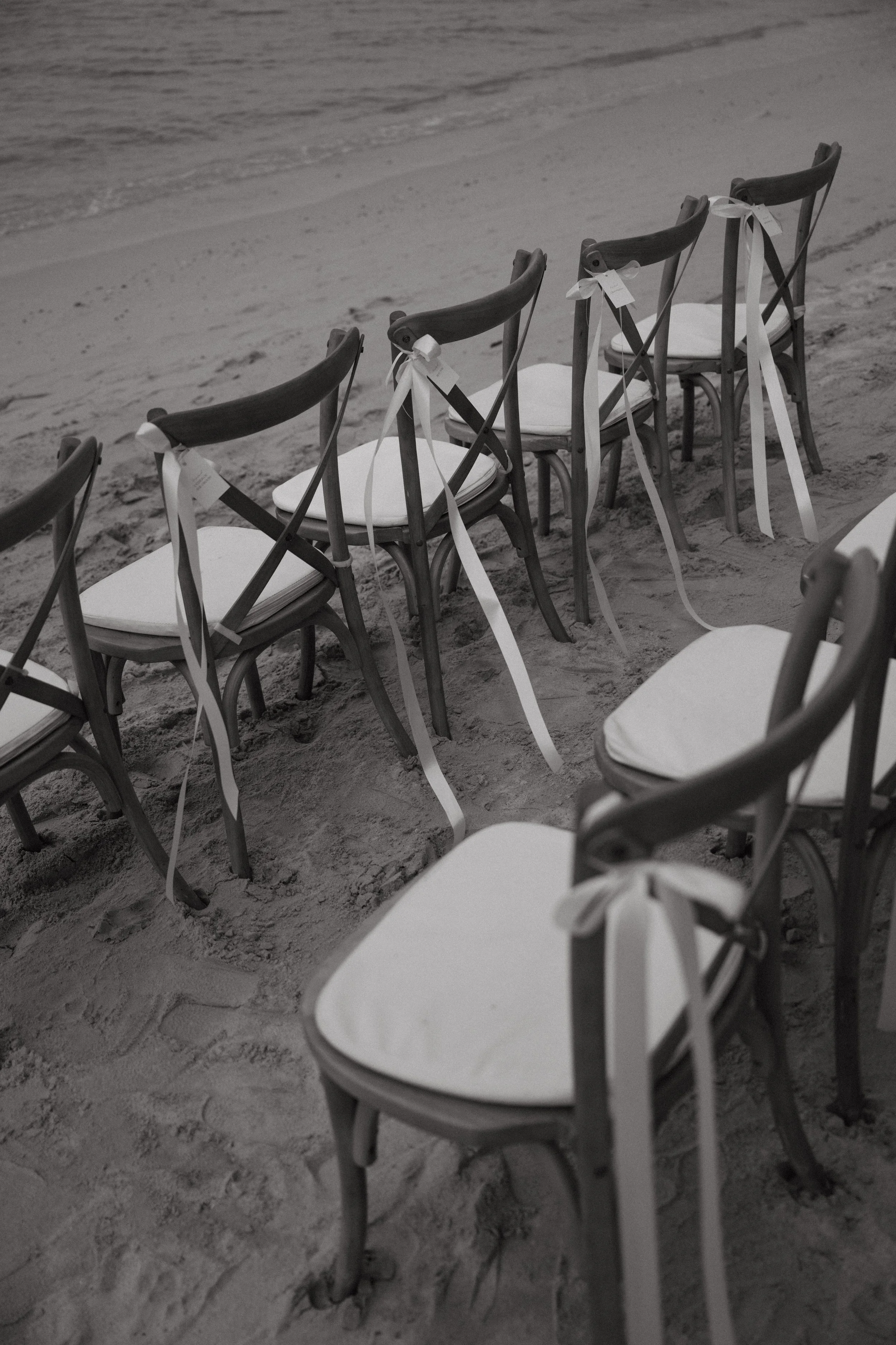 Wedding ceremony chairs with white ribbons arranged on the sand for an intimate beachfront wedding at Bangrak Beach, Koh Samui