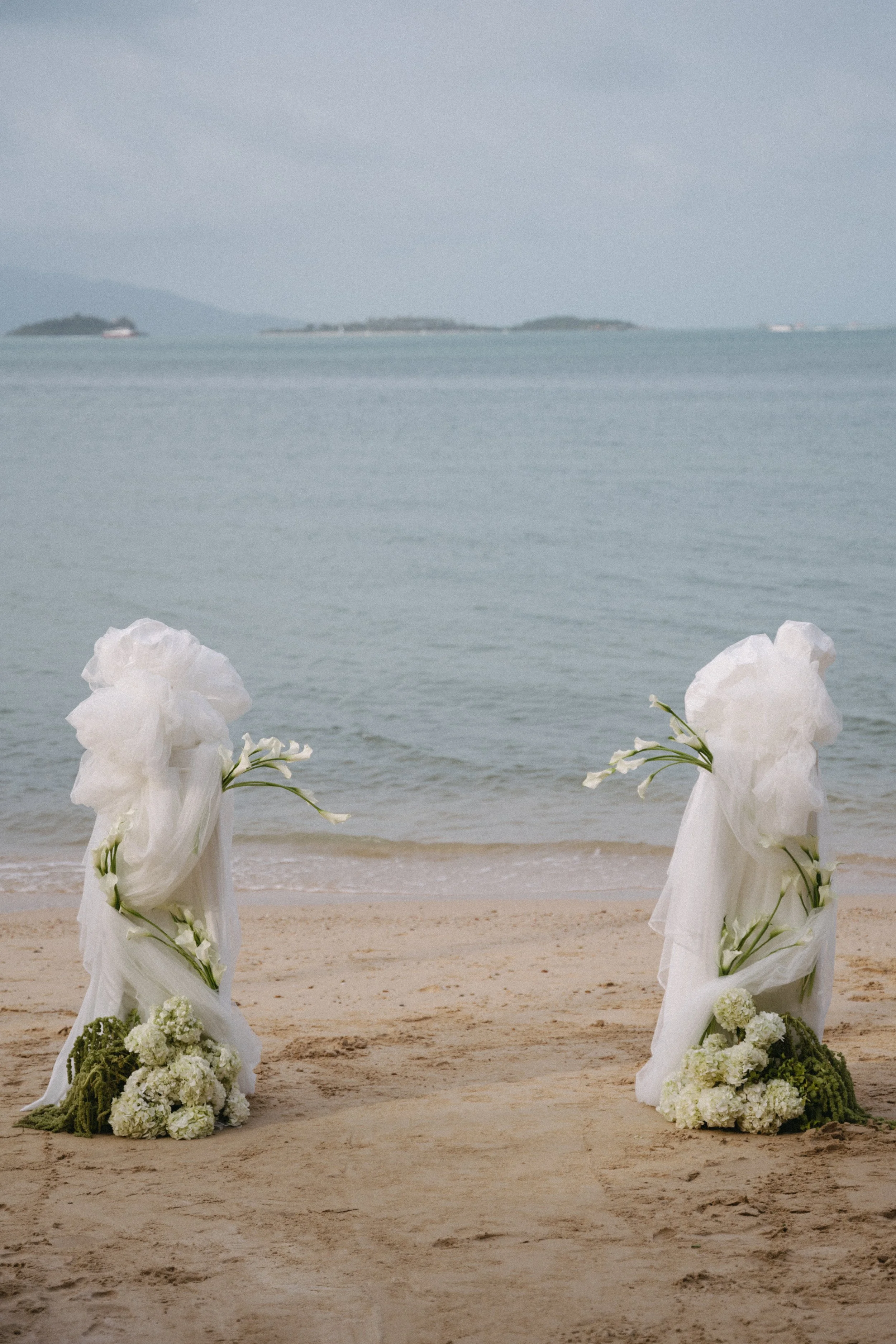 Beachfront wedding ceremony setup on Bangrak Beach in Koh Samui with sculptural white drapery and floral arrangements overlooking the ocean