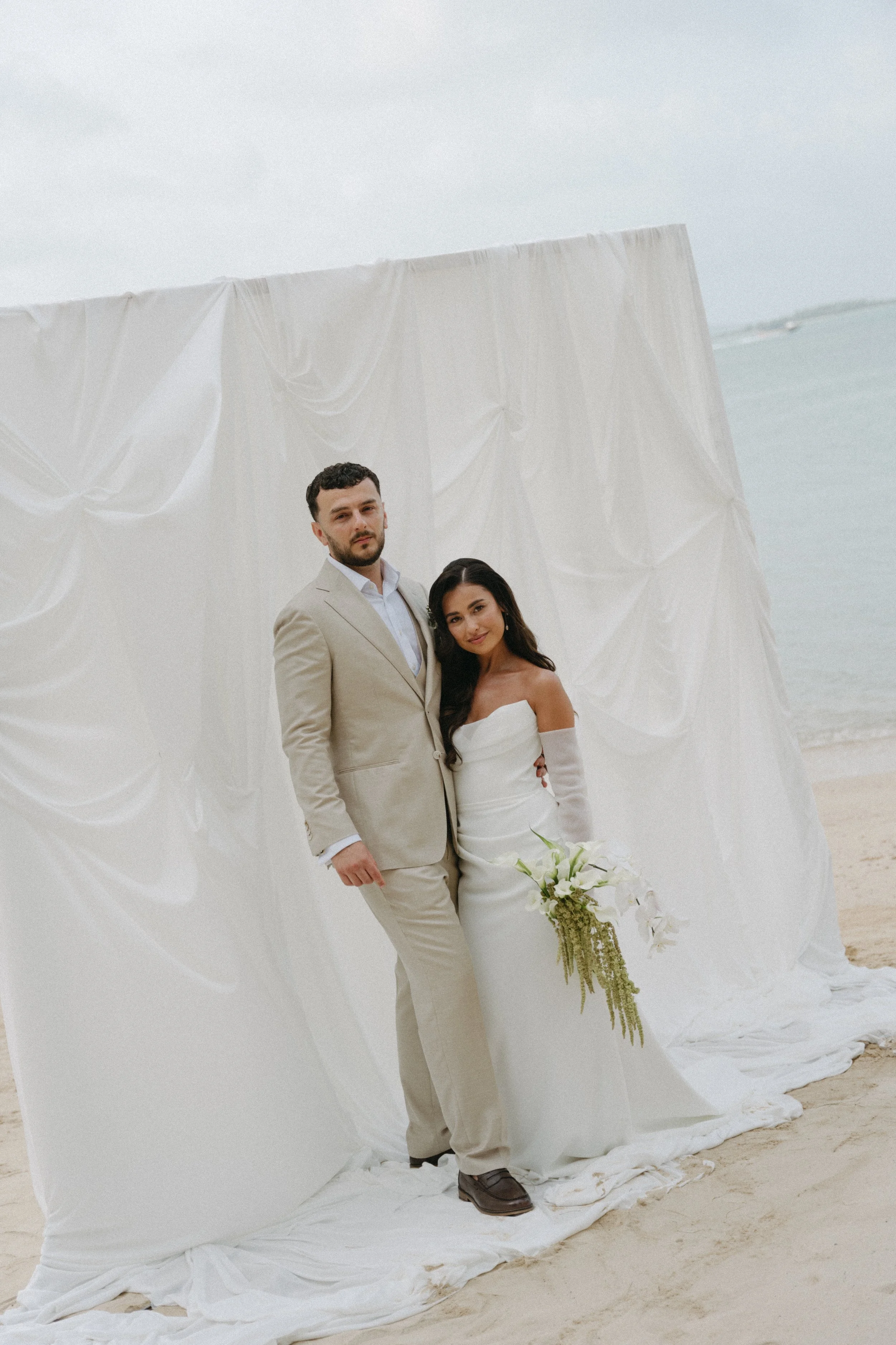 editorial wedding portrait of bride and groom on bangrak beach in front of draped background