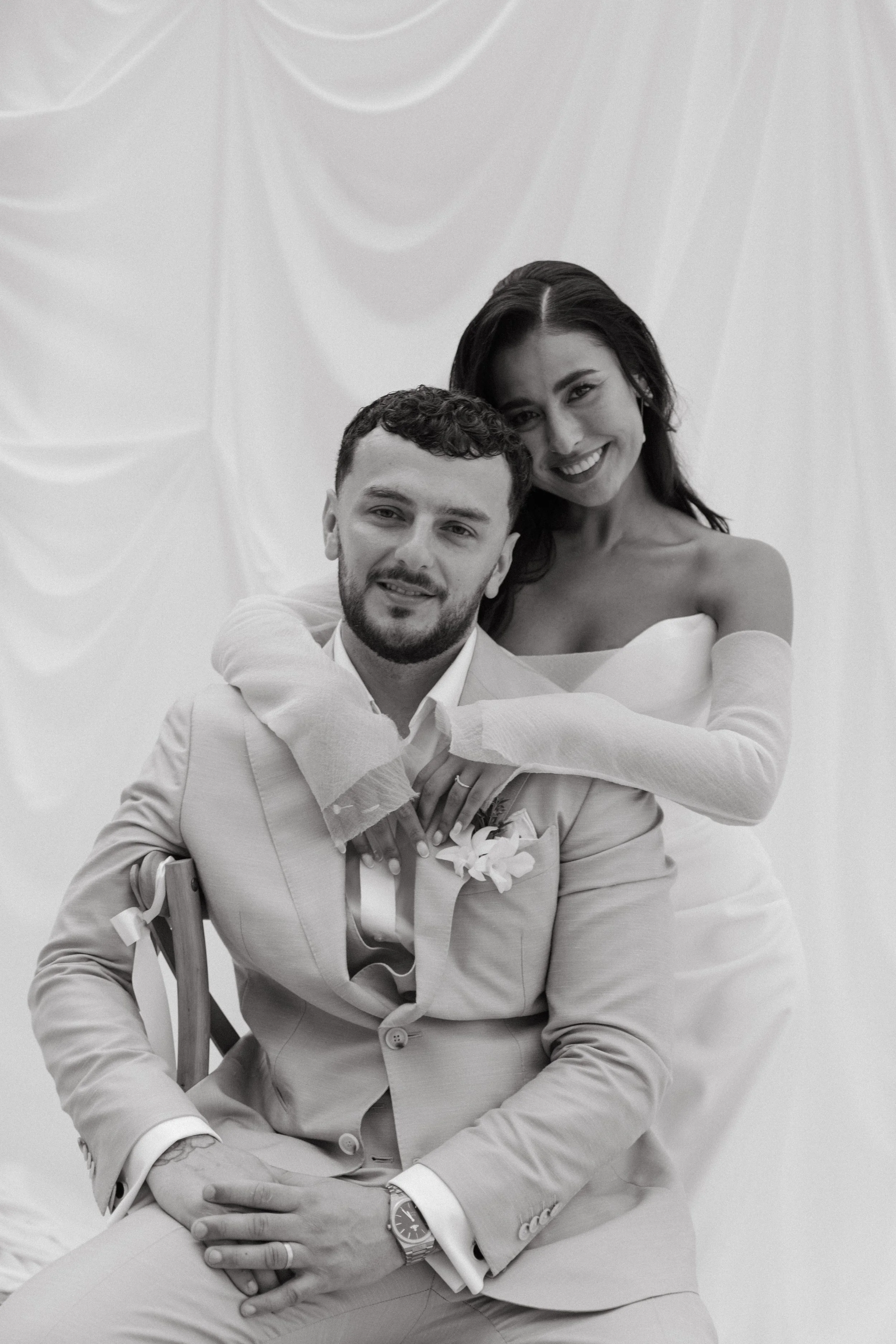 bride smiling as she embraces groom from behind after the ceremony