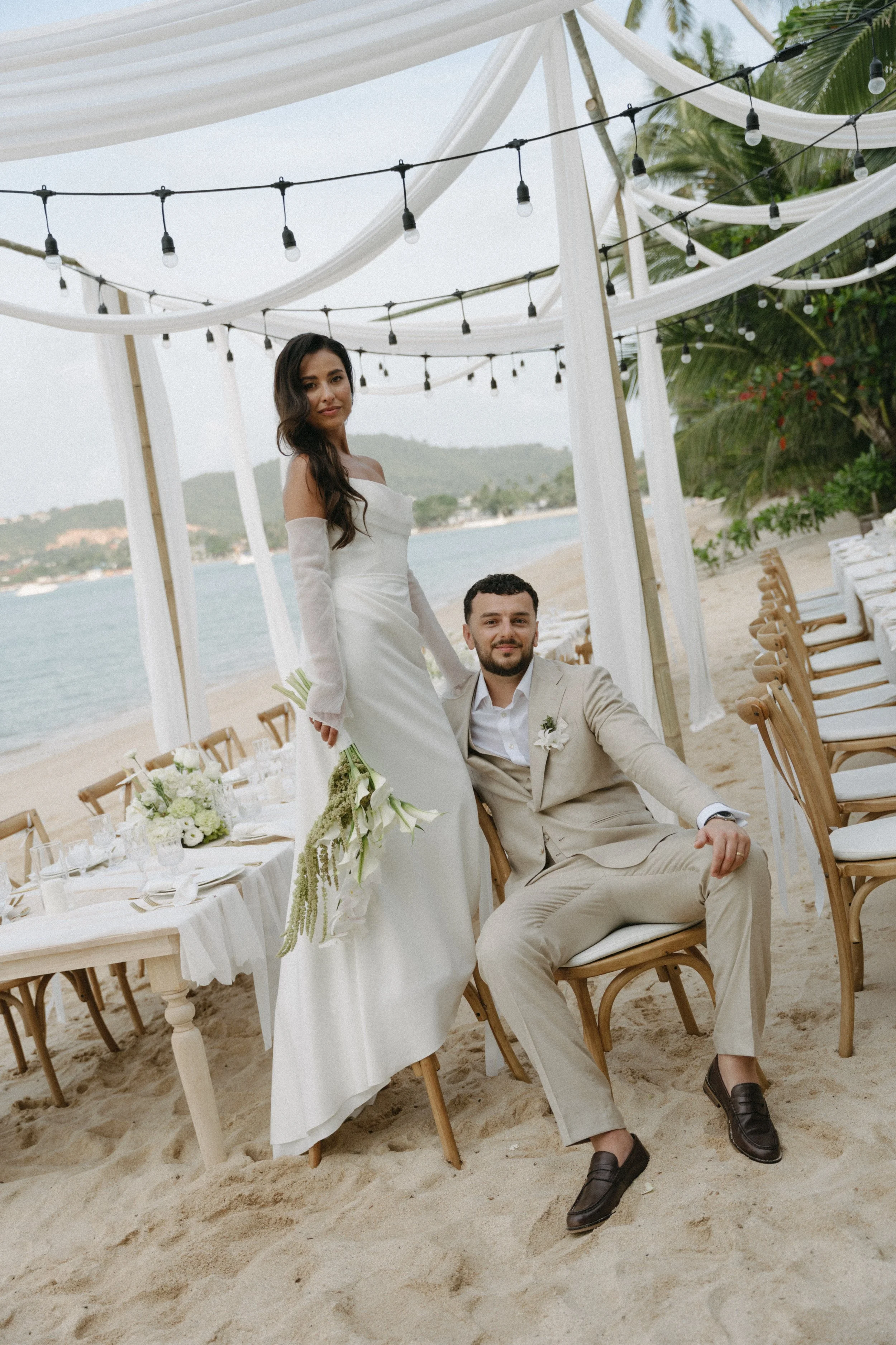 bride and groom sitting at outdoor reception setup on bangrak beach in koh samui
