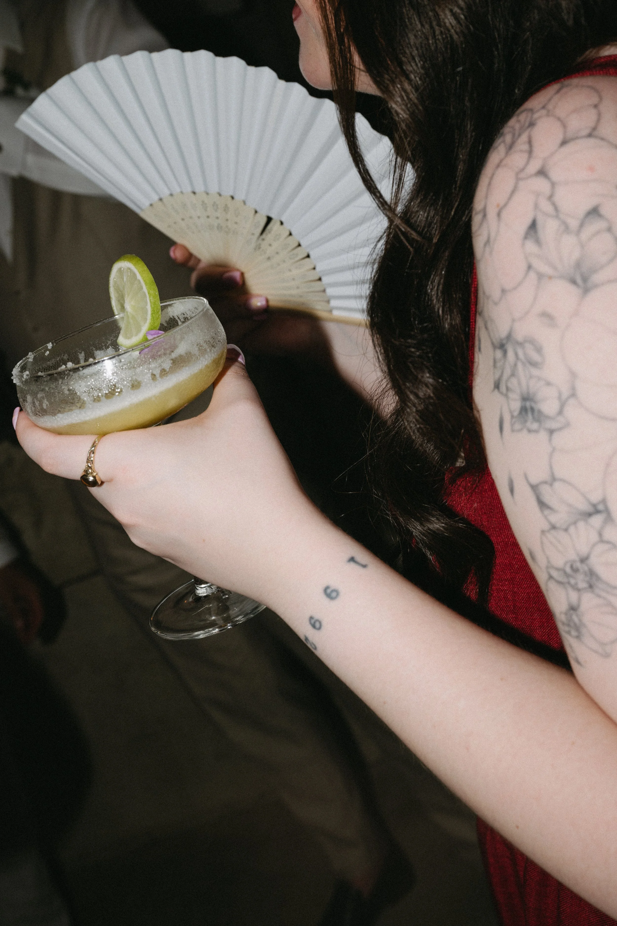 guest holding cocktail and white fan 