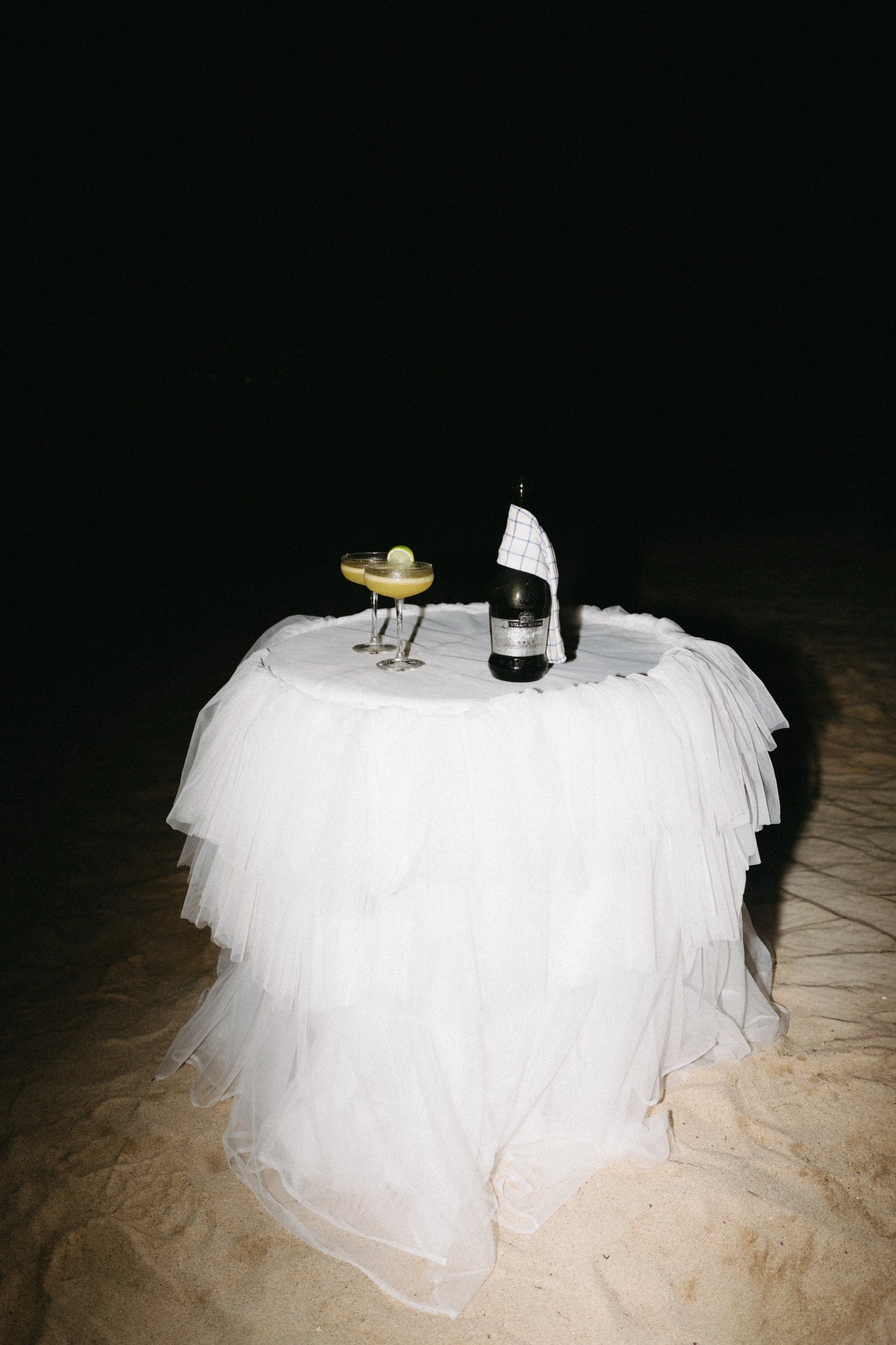 Styled wedding cake table draped in white tulle at a night reception on Bangrak Beach, Koh Samui