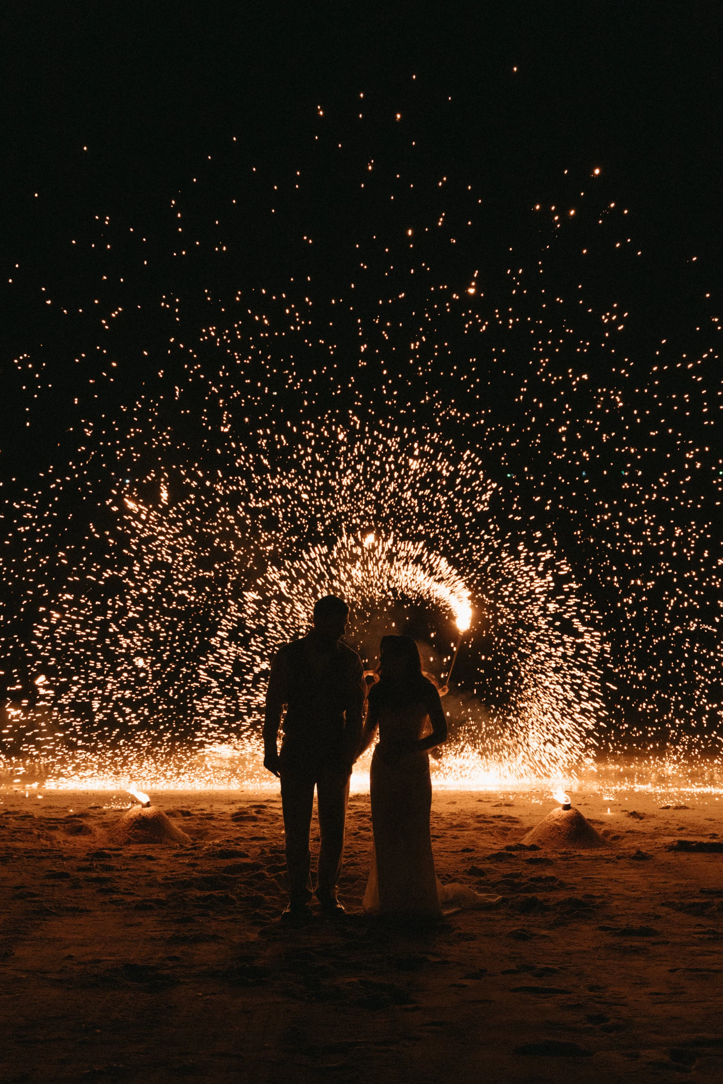 Couple silhouetted against a dramatic sparkler display on Bangrak Beach at their Koh Samui destination wedding