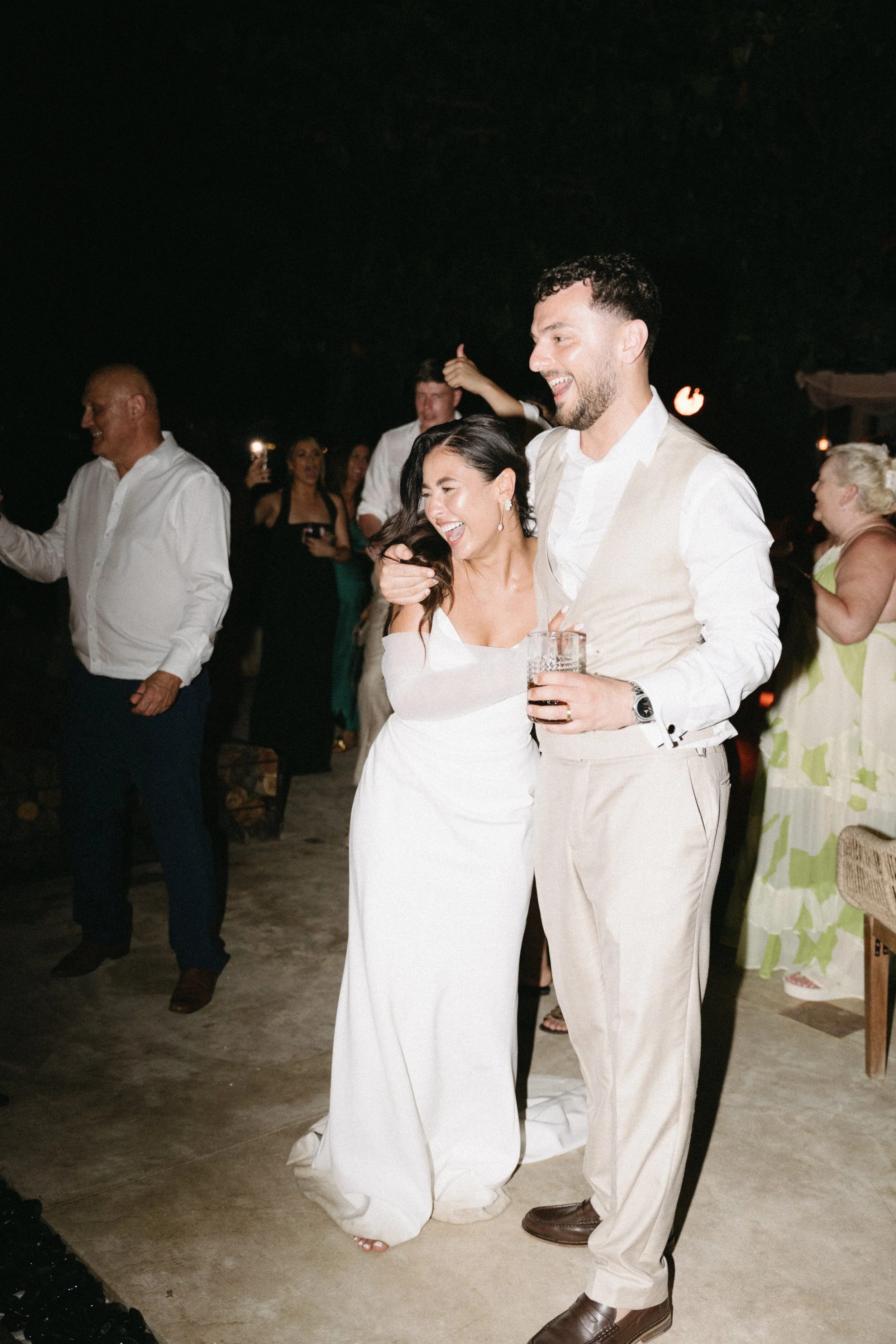 Bride and groom laughing with guests during evening wedding celebrations at Odyssey Mansion, Bangrak Beach, Koh Samui