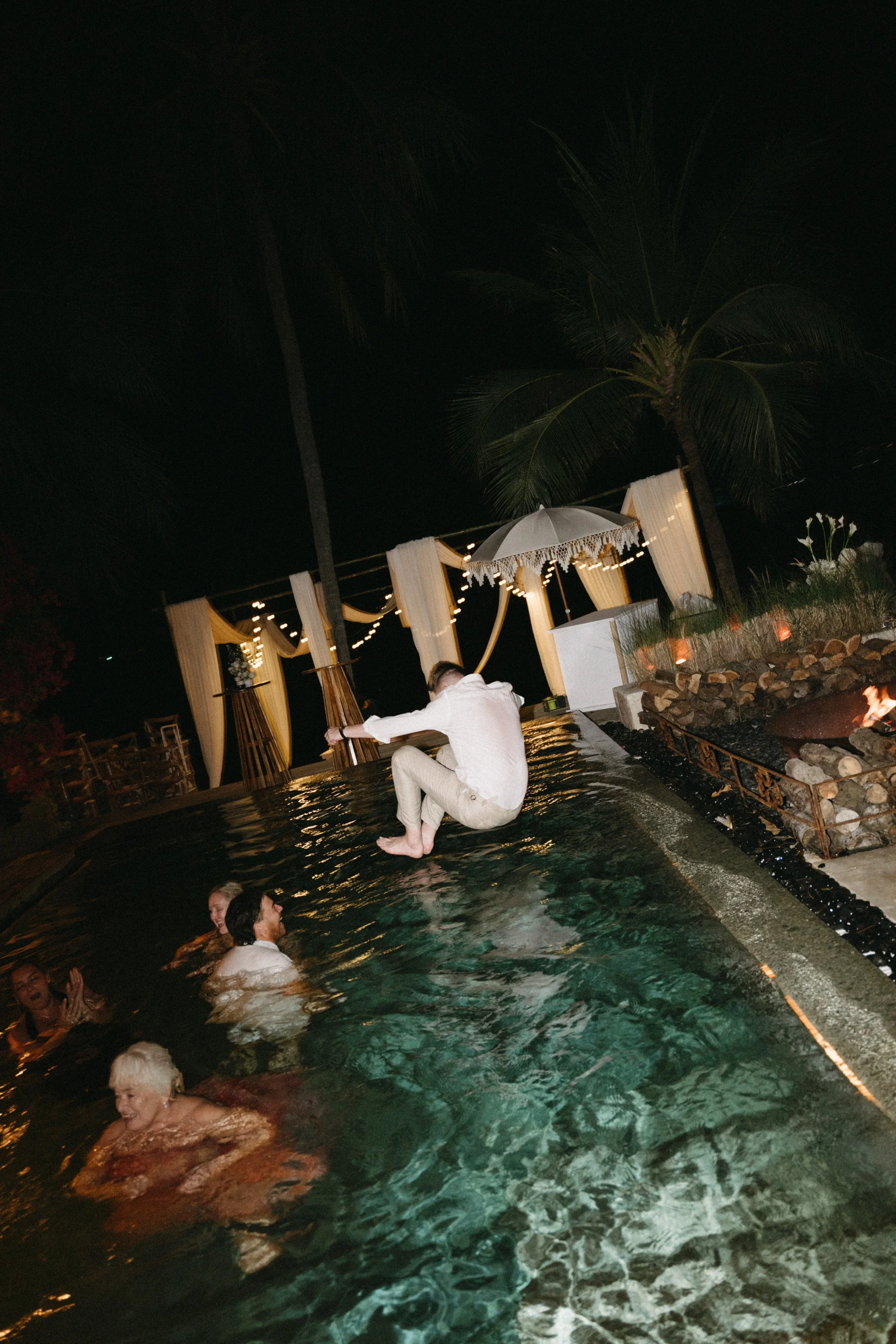 Wedding guests enjoying the pool at night during a destination wedding after-party at Odyssey Mansion, Koh Samui