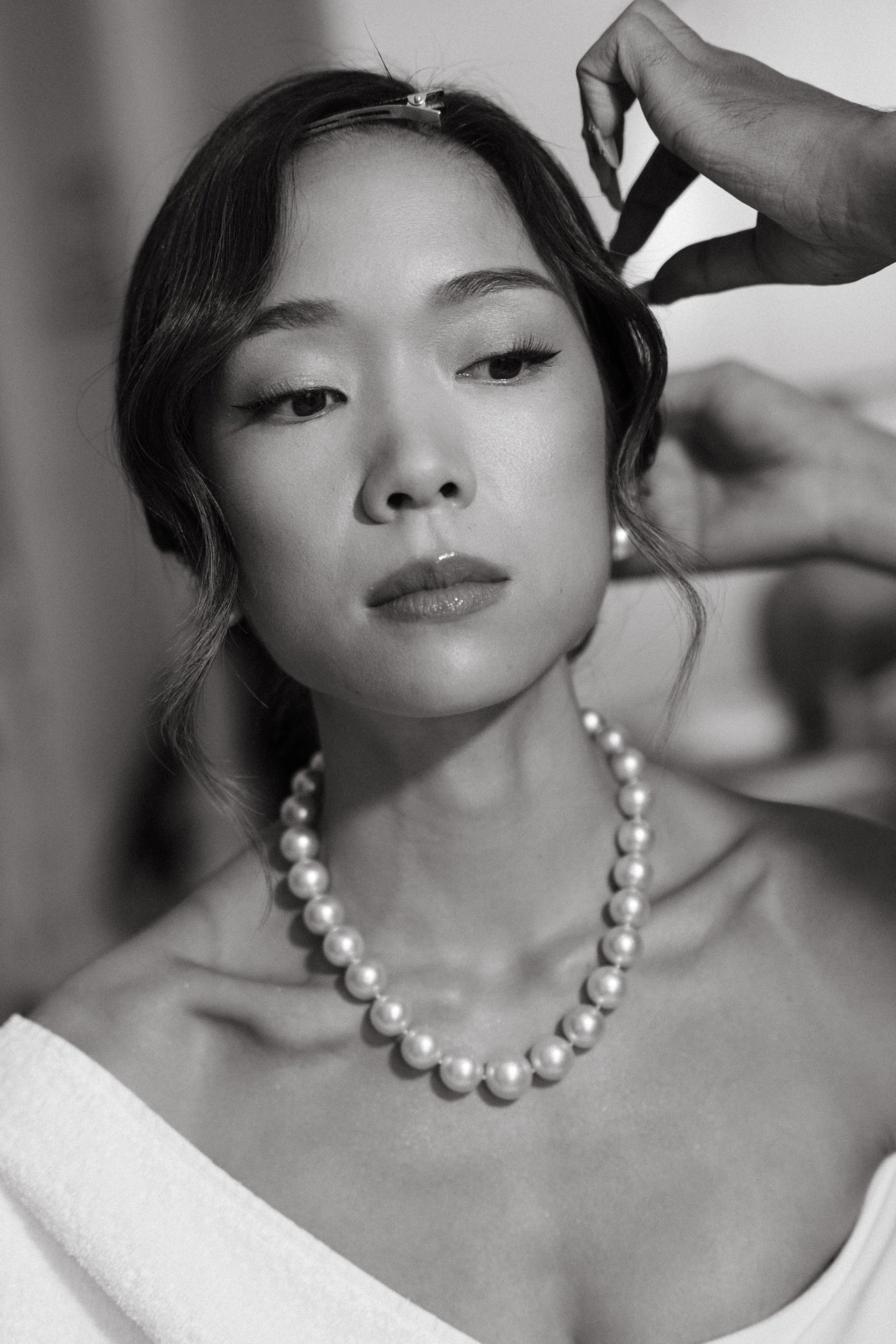 close up of bride wearing pearls and having hair styled before wedding ceremony 