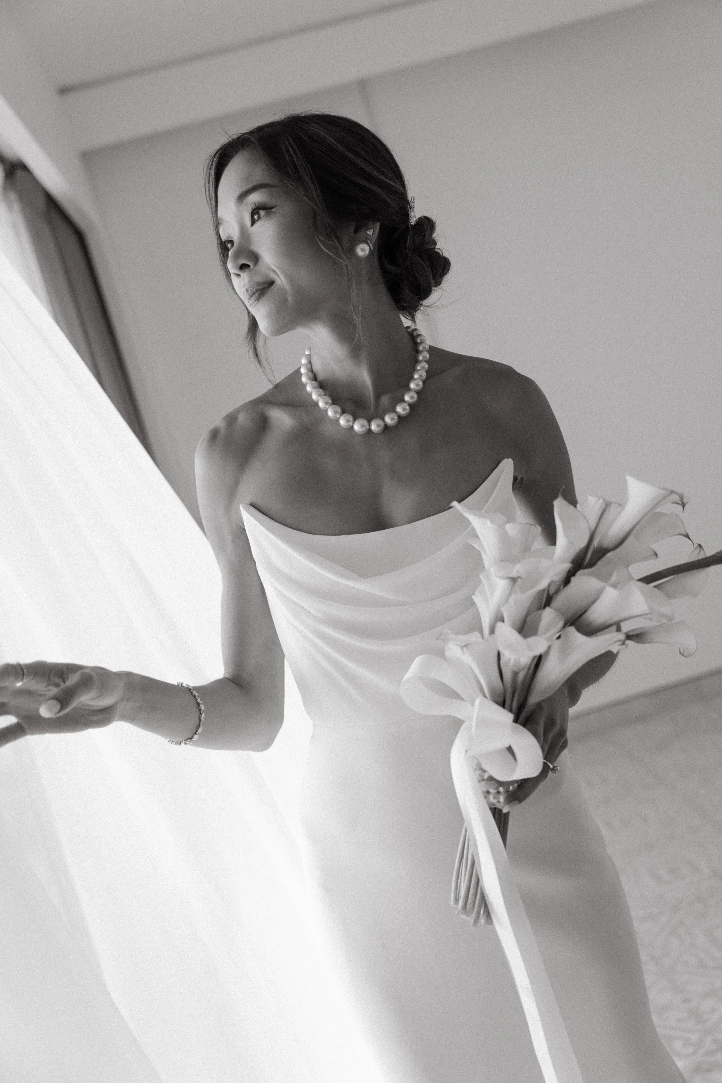 Bride in off the shoulder alex perry wedding dress holding calla lily bouquet, black and white editorial bridal portrait
