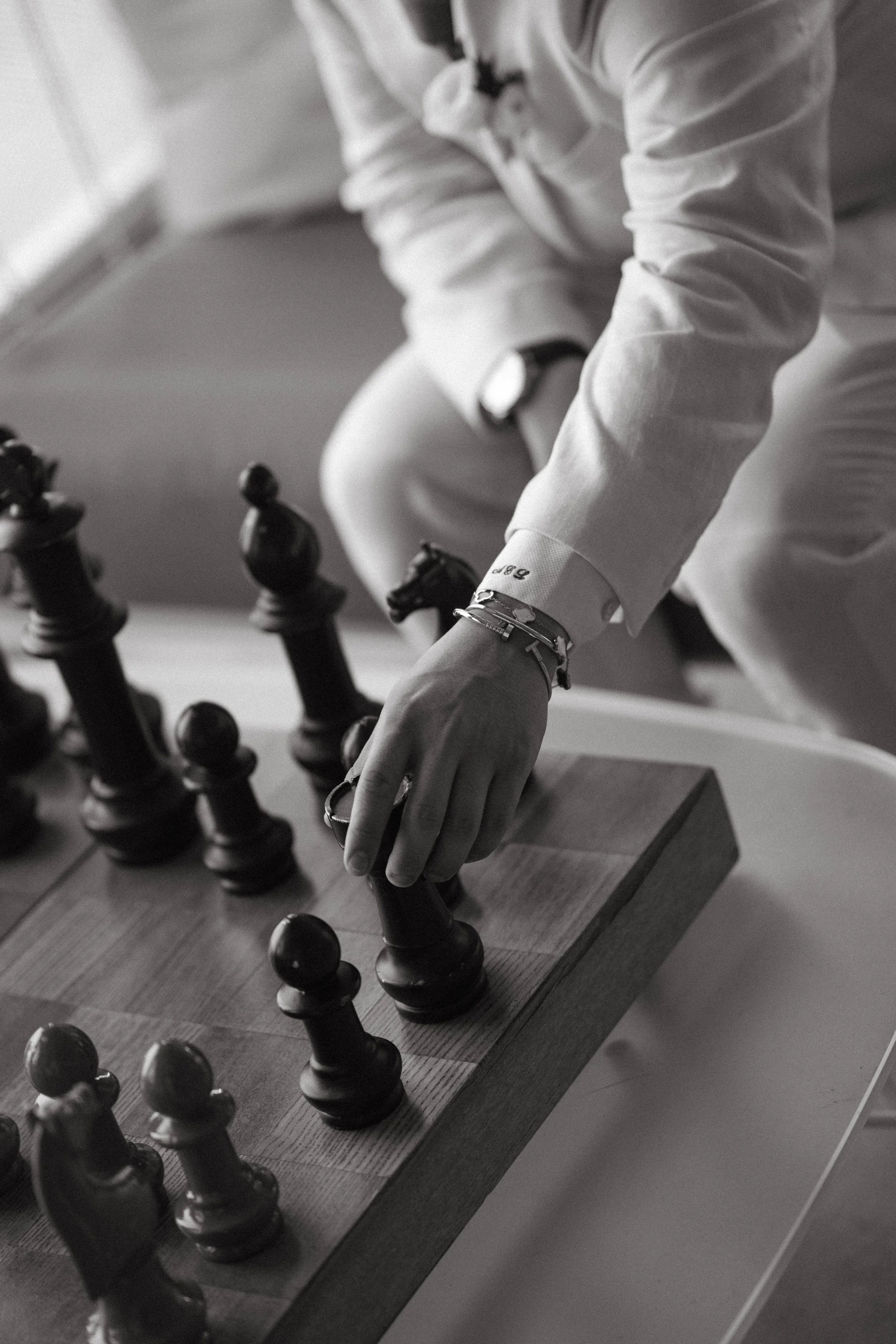 Close-up of hands playing chess during wedding morning, black and white documentary detail shot