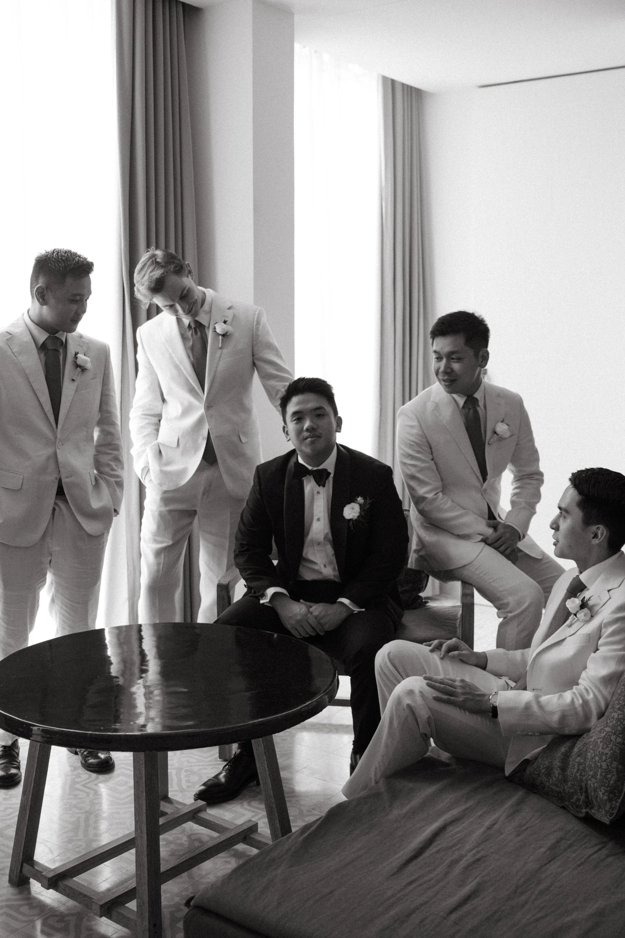 Groom and groomsmen in suits getting ready together, documentary-style wedding morning photo