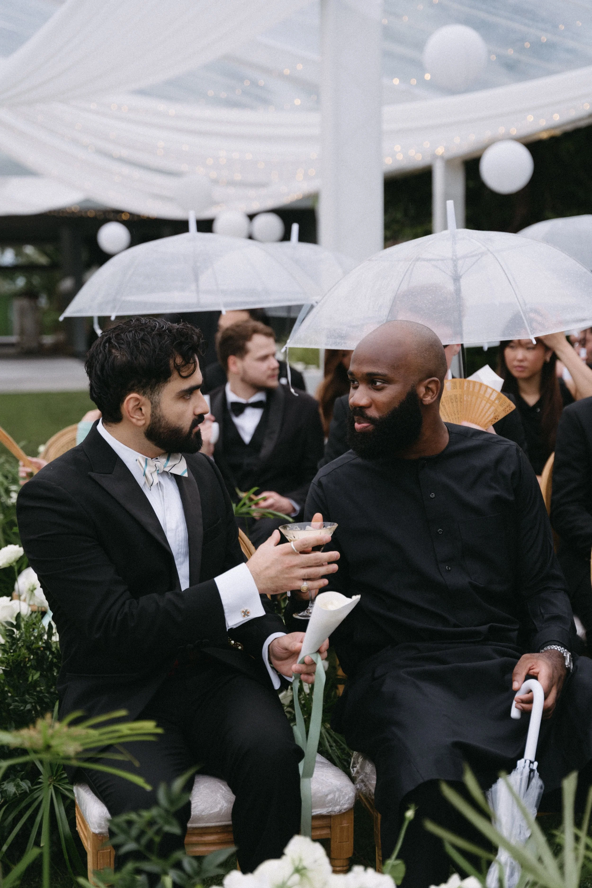 Wedding guests talking under umbrellas during rainy Phuket ceremony