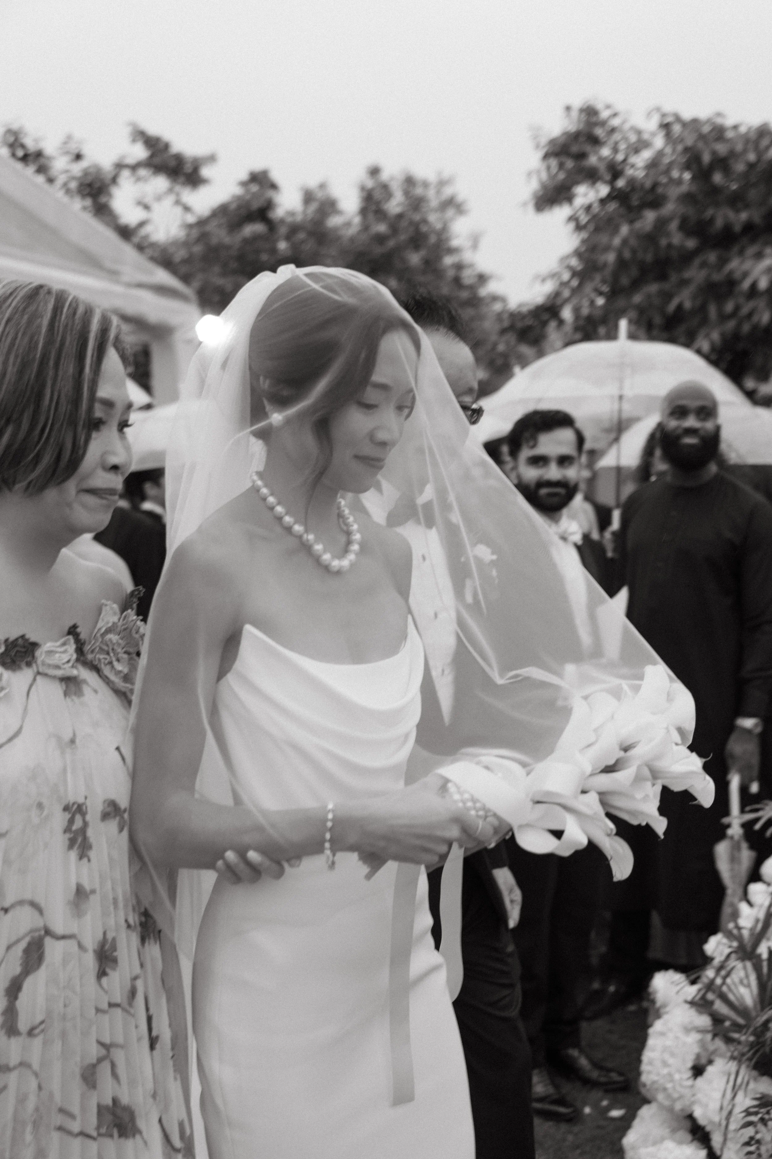 Bride walking down aisle with mum in cathedral veil, black and white rainy ceremony portrait