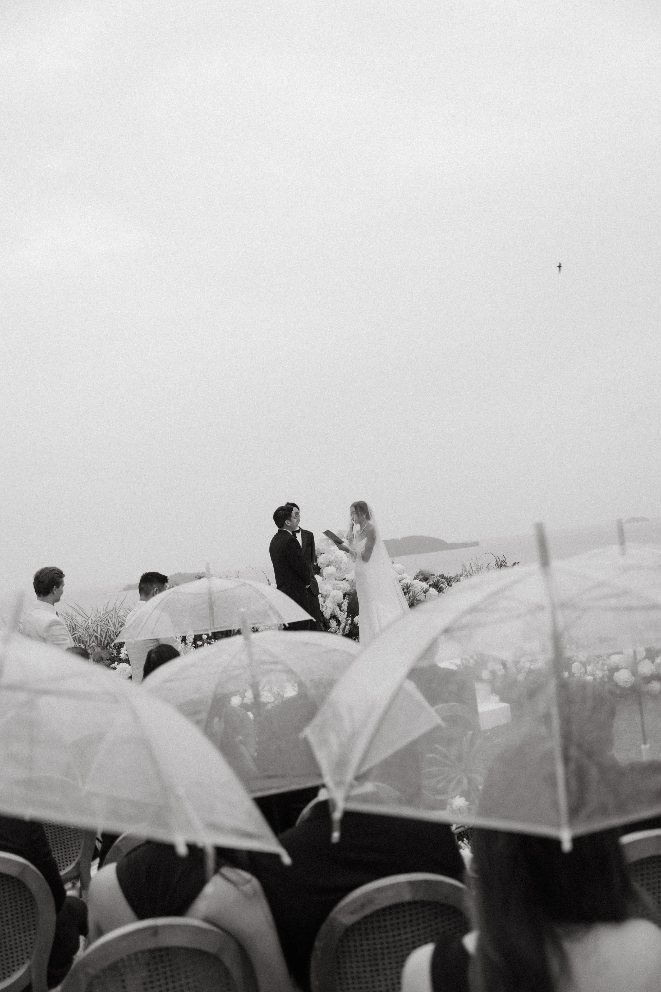 Wedding guests seated under umbrellas with ocean view at COMO Point Yamu ceremony