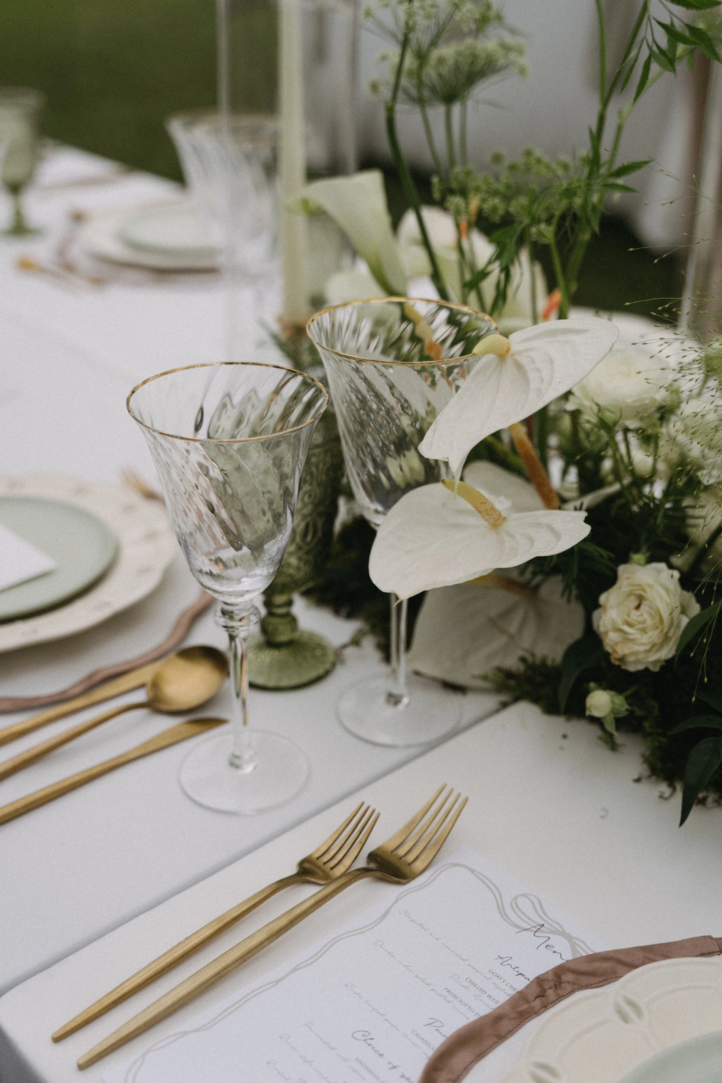 Table setting with crystal glassware, gold cutlery and white anthurium floral centrepiece
