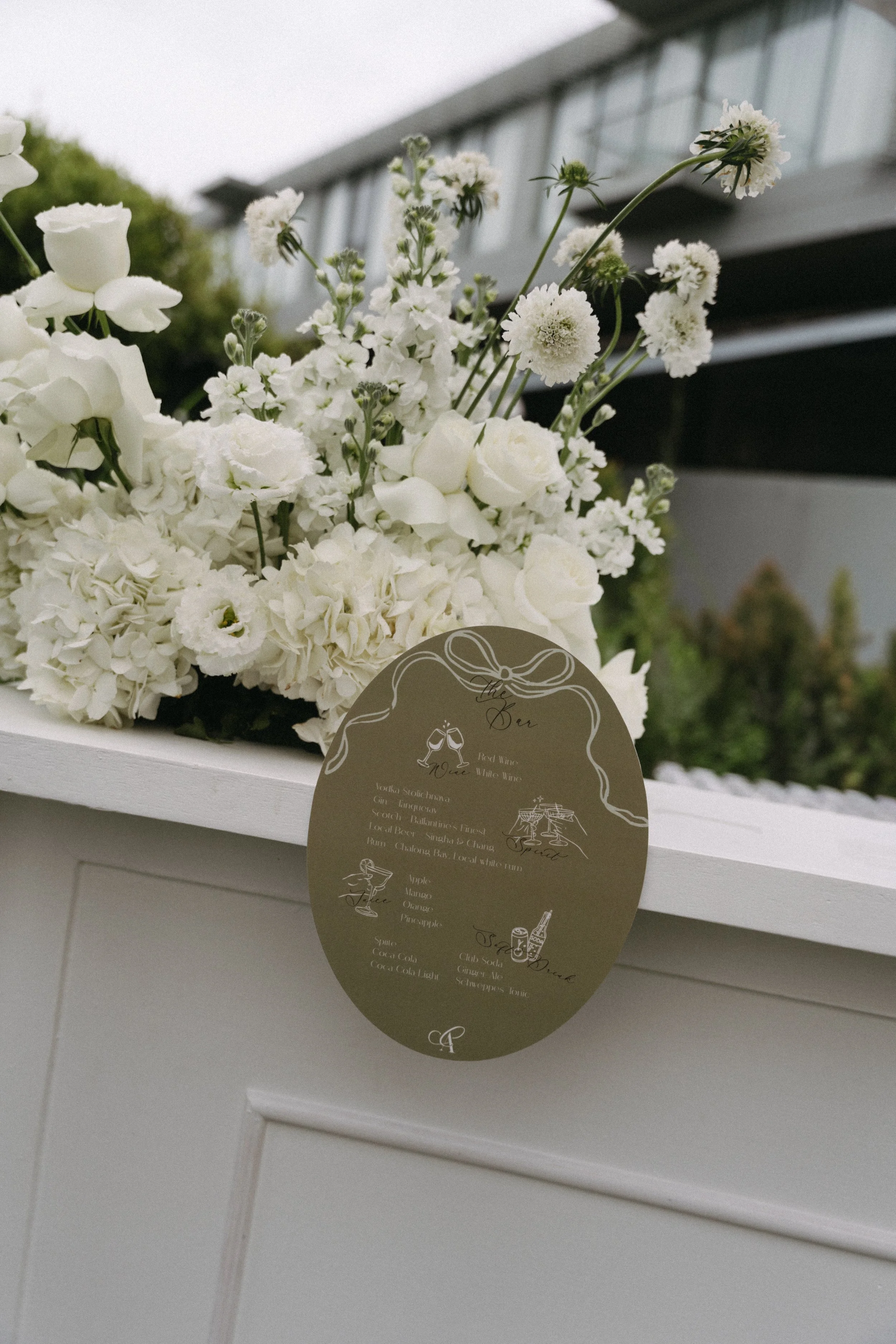 White floral arrangement beside drink menu sign, outdoor reception styling at COMO Point Yamu