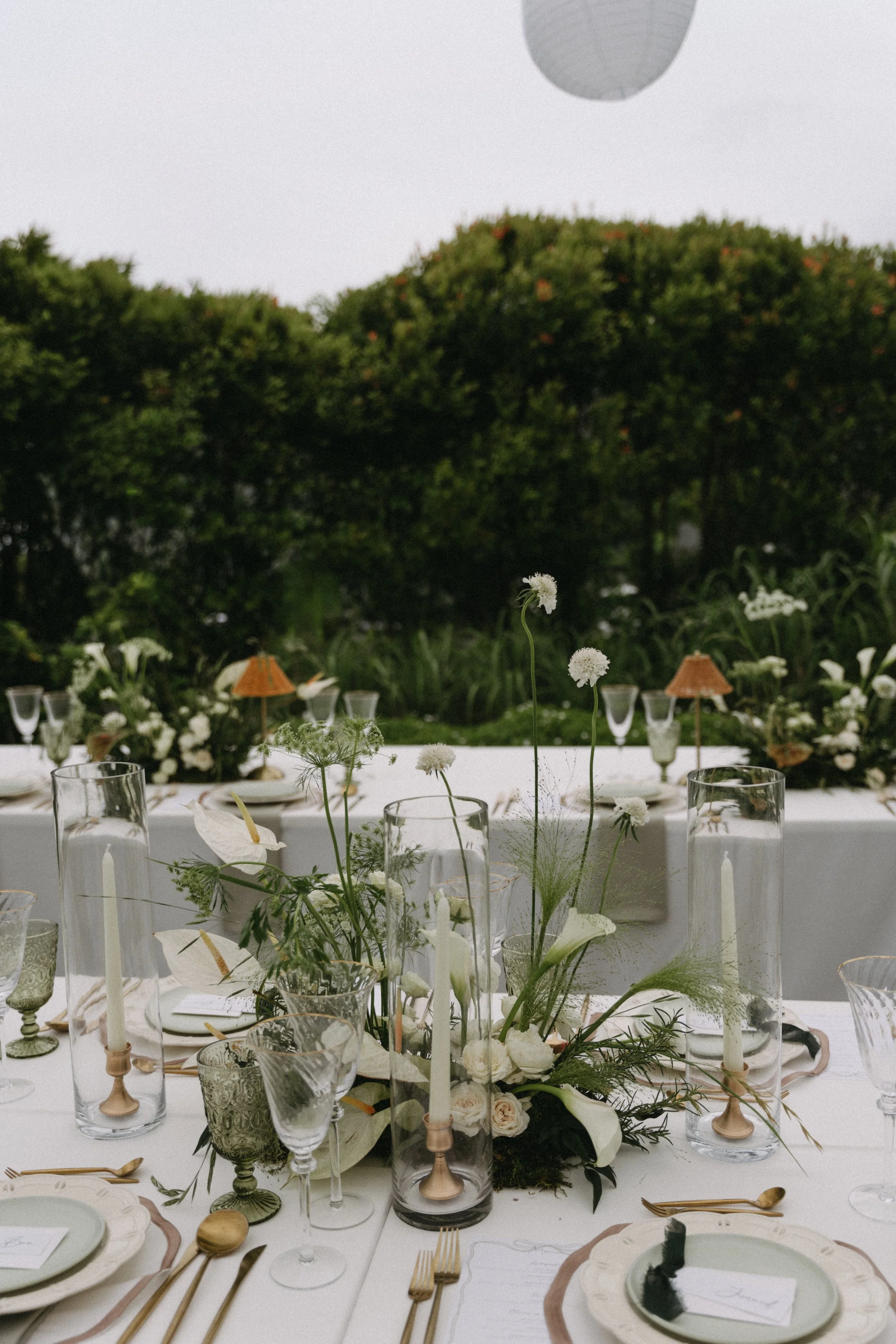 Outdoor reception tablescape with tapered candles and greenery at dusk