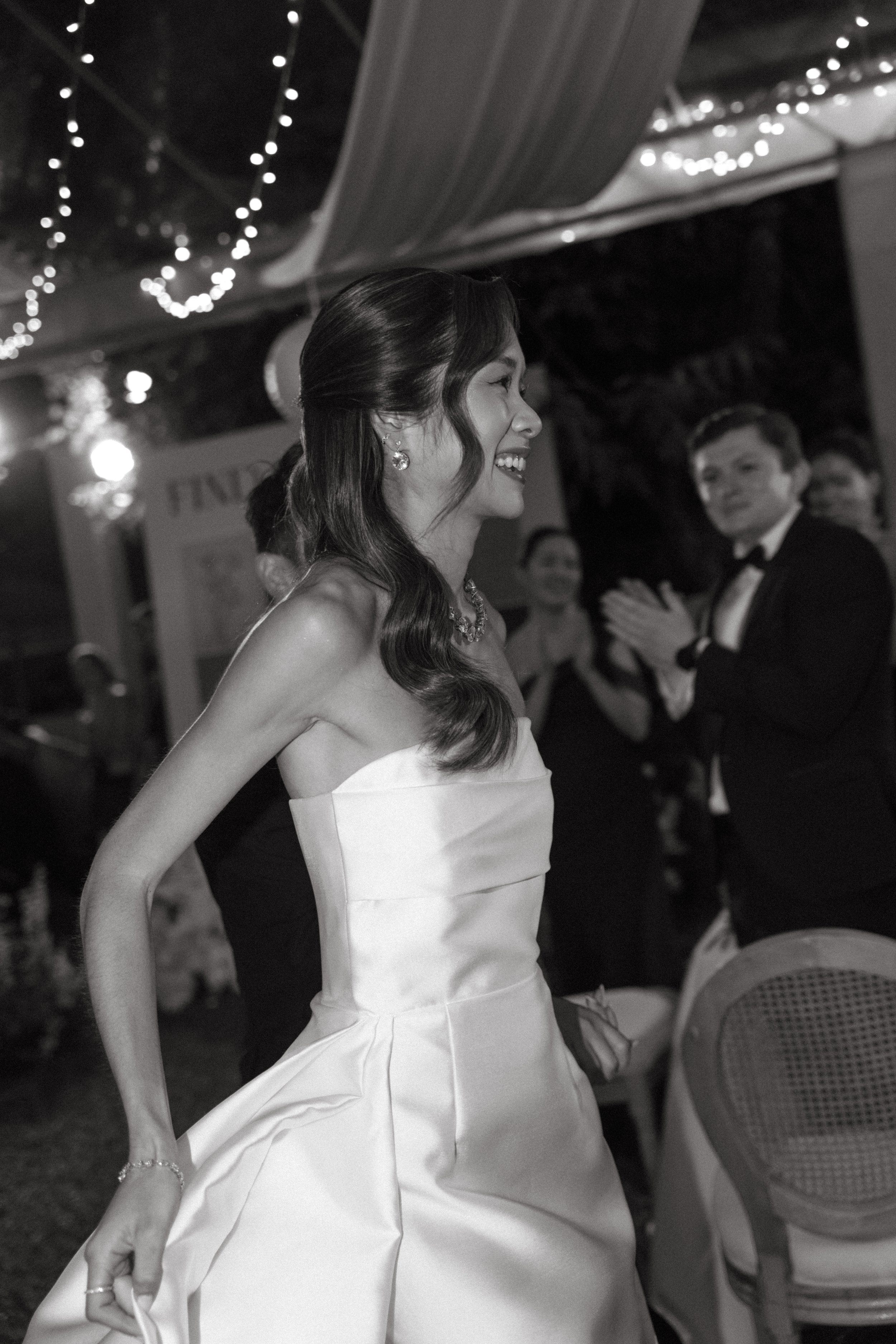 Bride in solace london mini dress entering reception under fairy lights to cheering guests