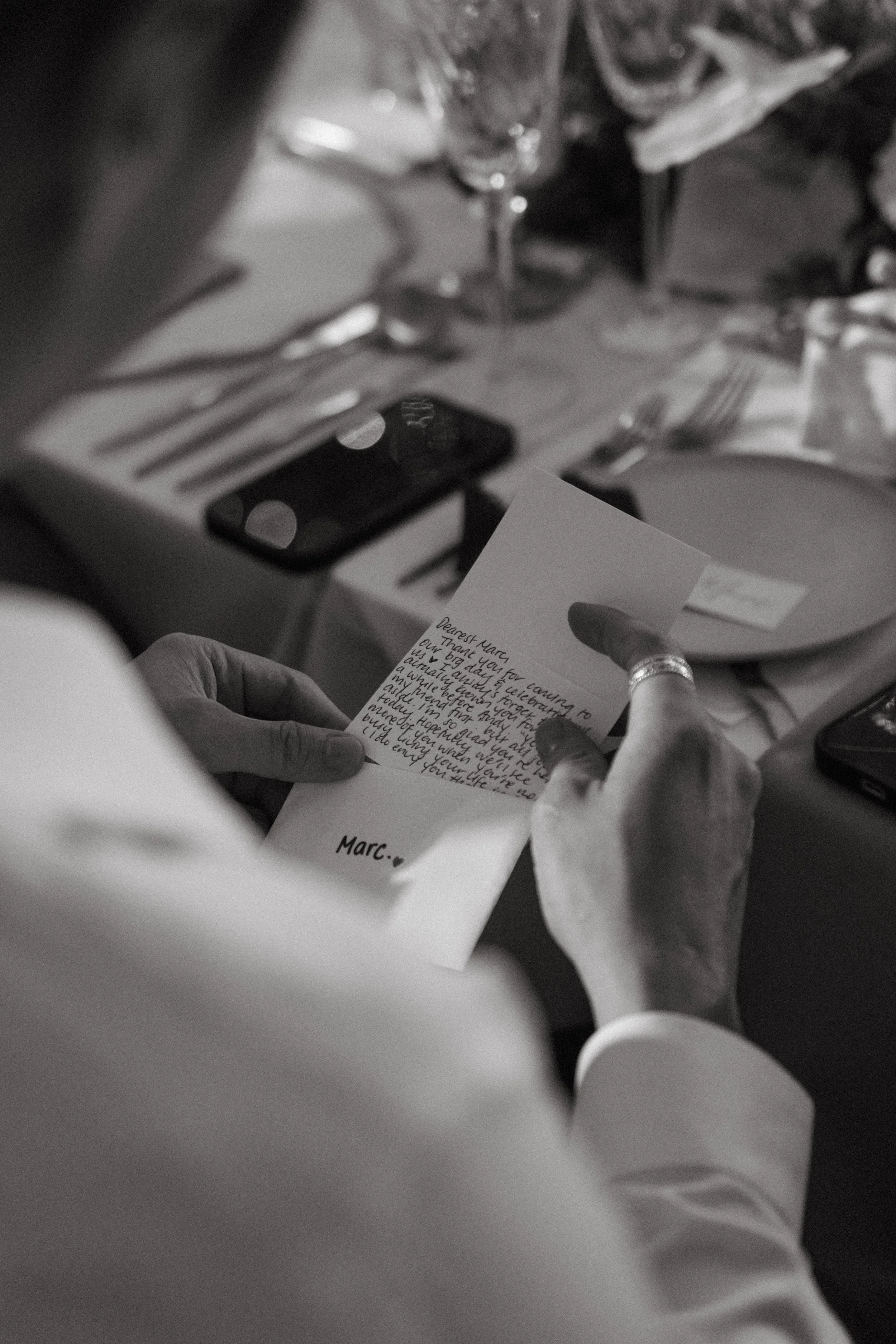 Close-up of guest's hands holding handwritten note at reception table